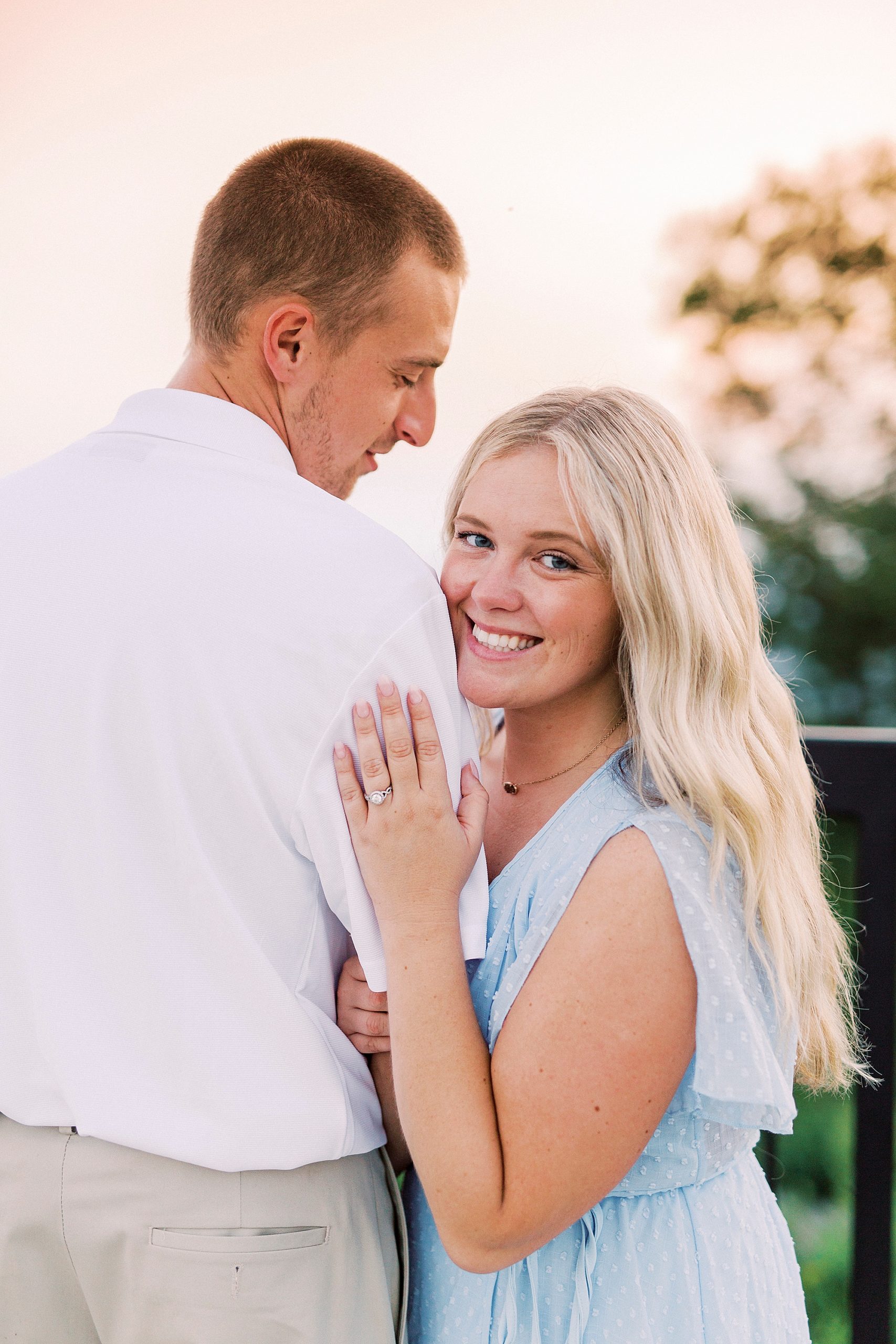 bride hugs groom's arm showing off engagement ring