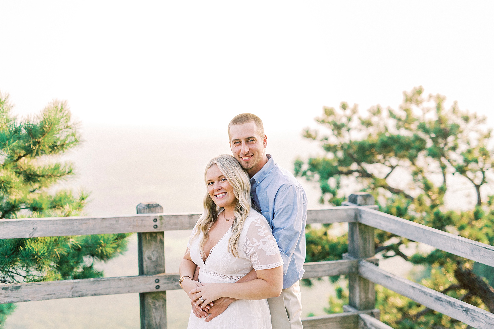 bride and groom hug on overlook at Pilot Mountain