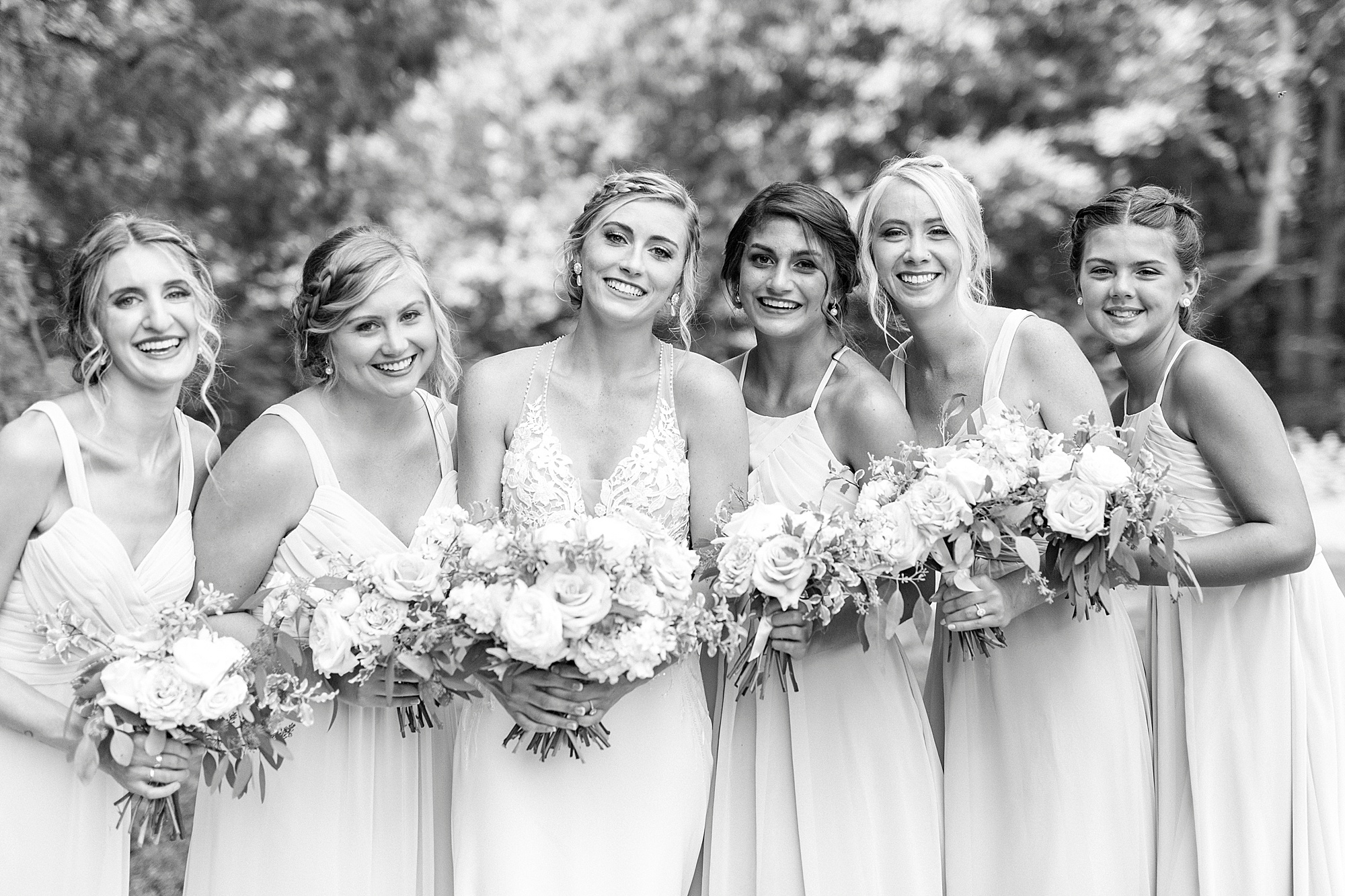bride and bridesmaids stand together with bouquets