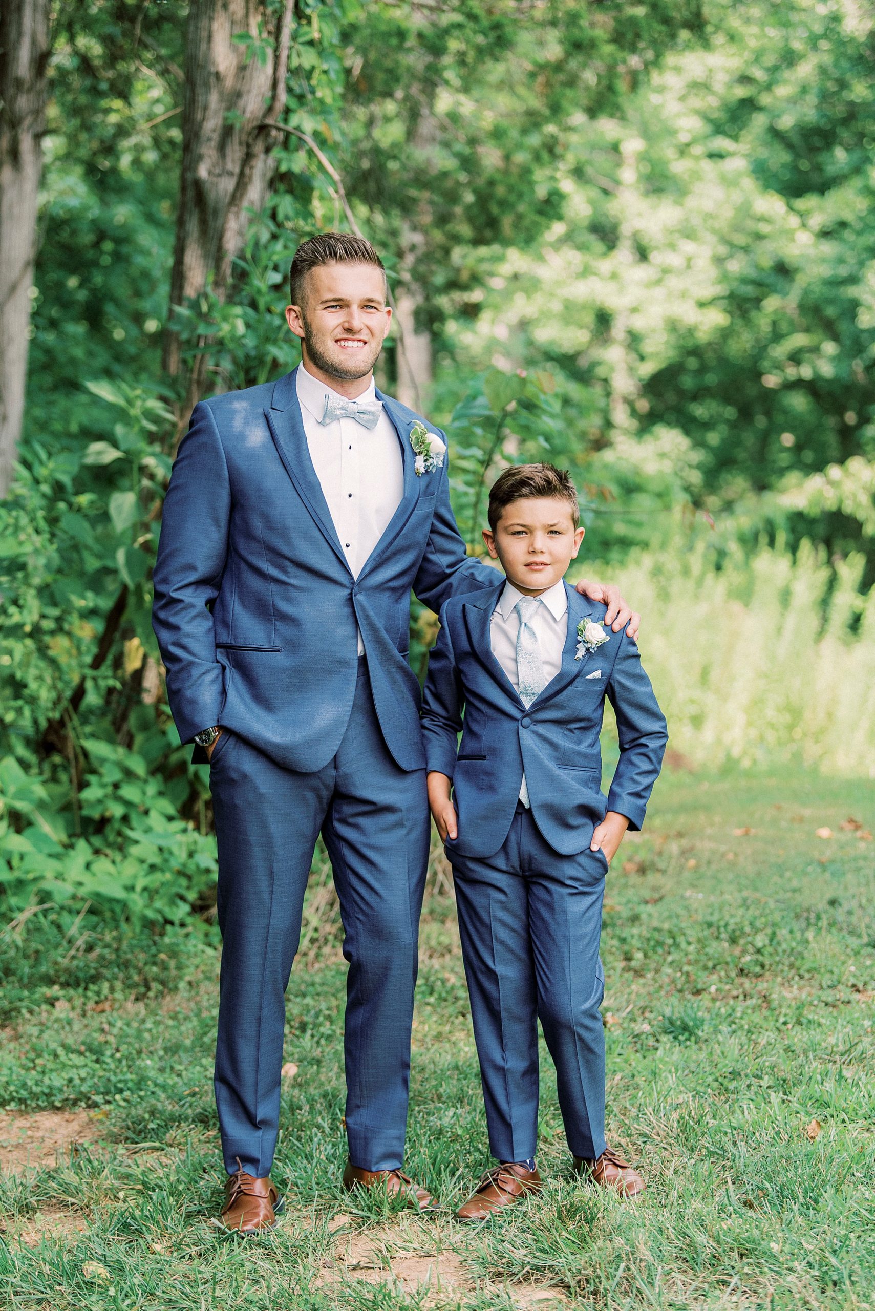 groom and ring bearer pose in navy suits