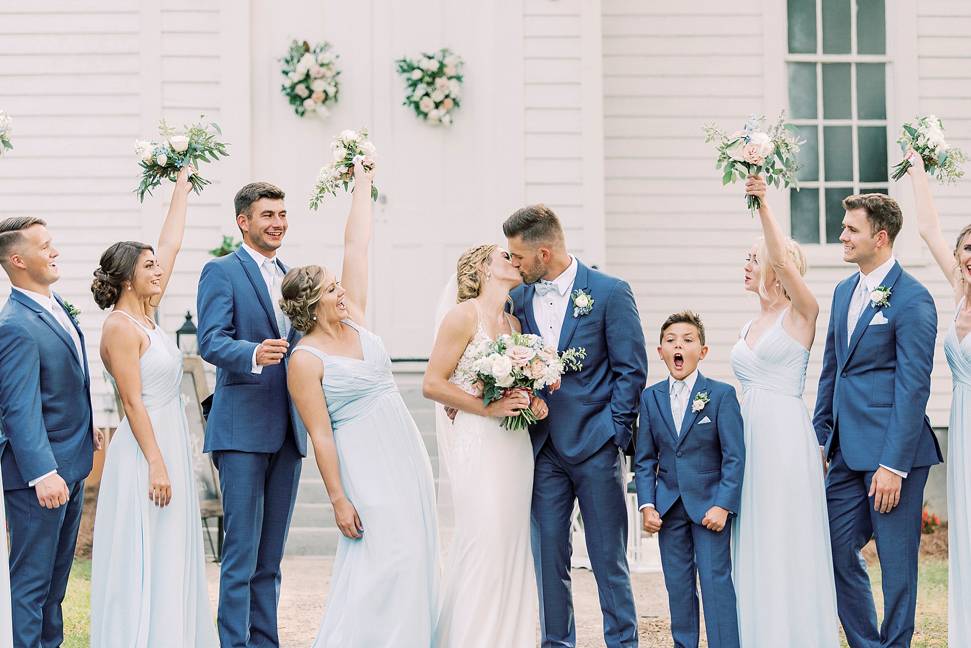 bride and groom kiss while wedding party cheers