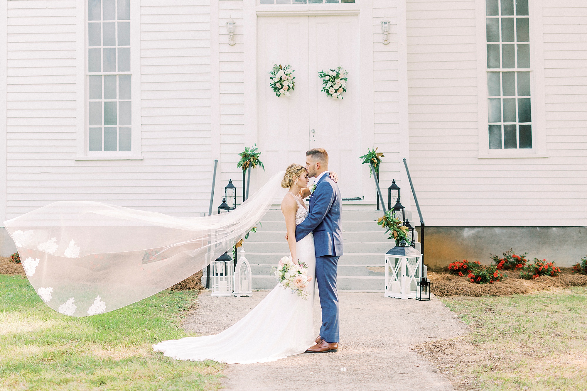 groom kisses bride's forehead during portraits outside Winston-Salem NC church