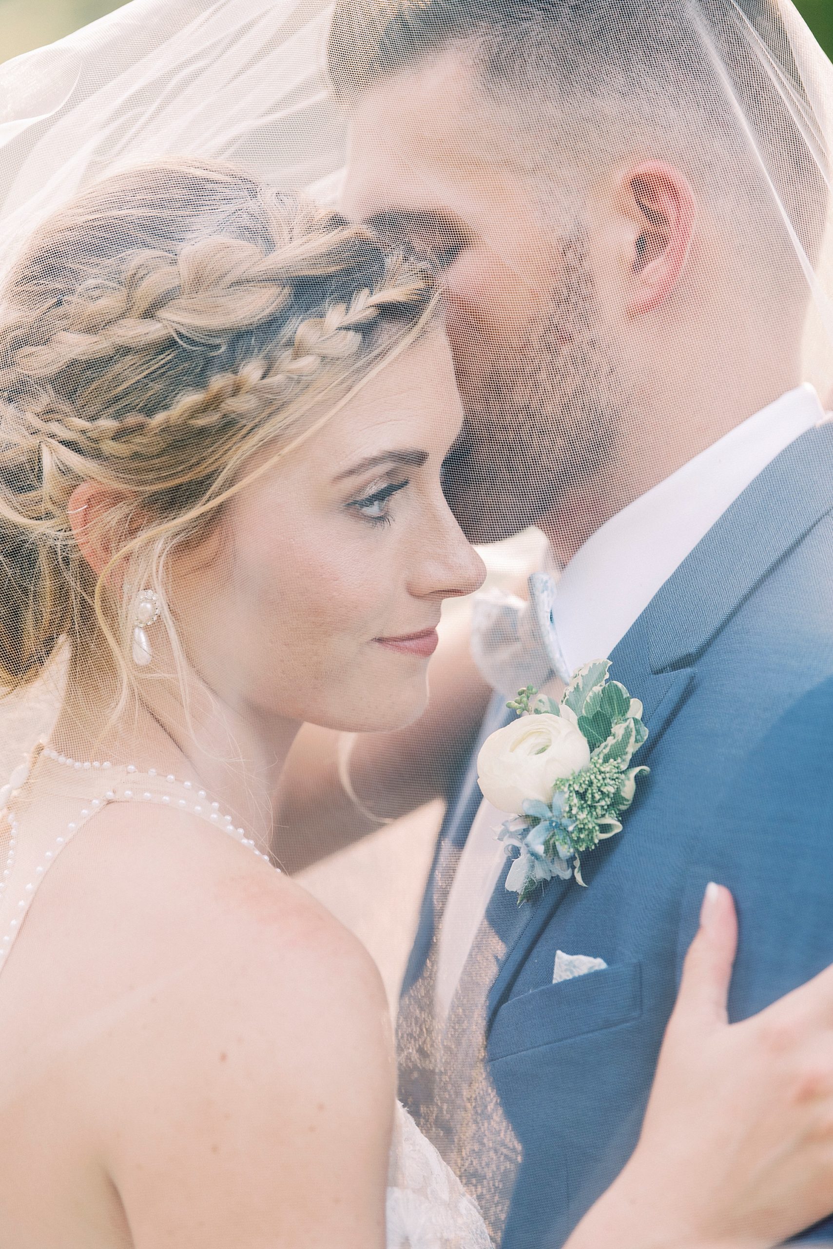 bride and groom pose under veil outside Winston-Salem NC church