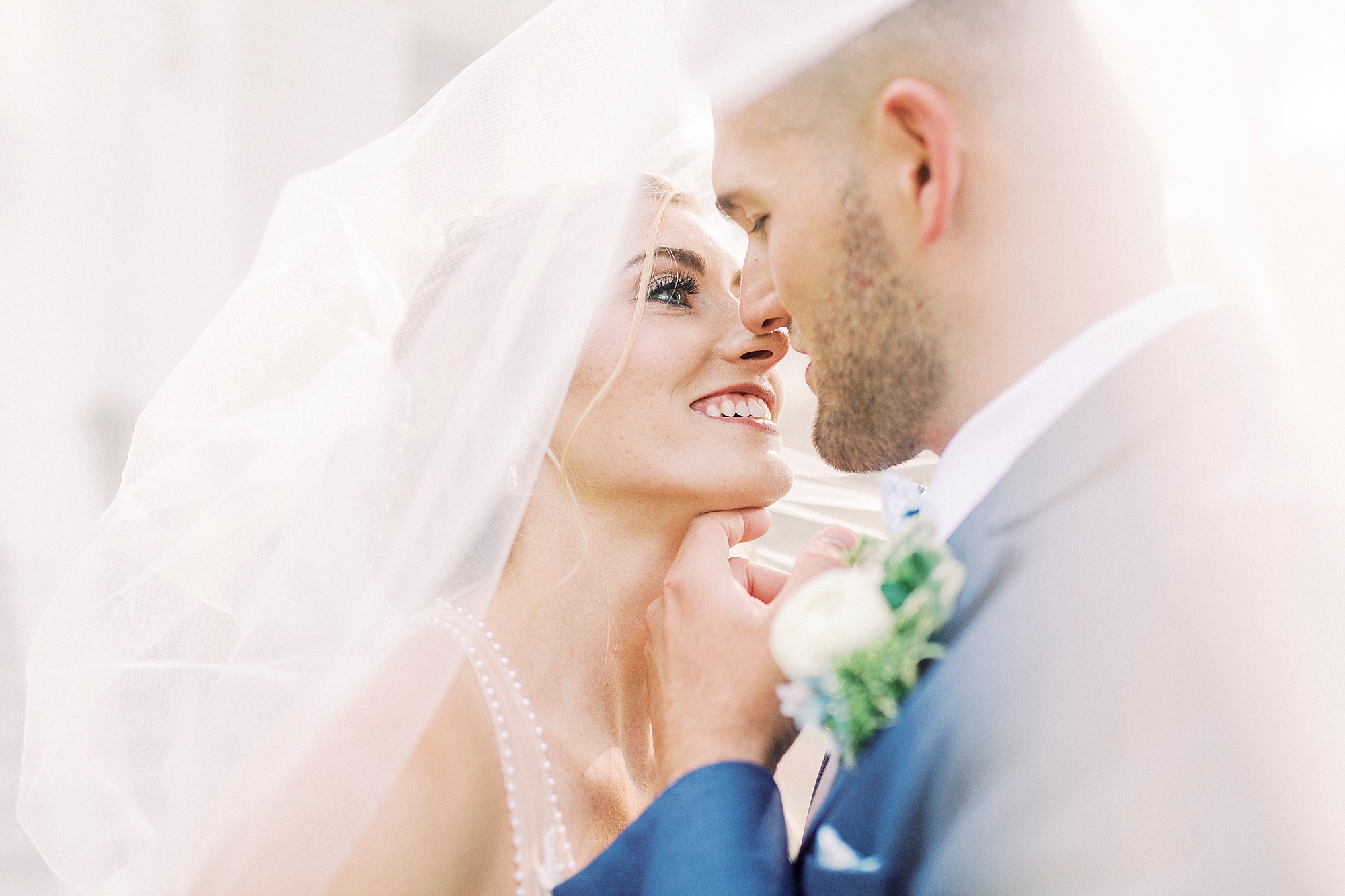 bride and groom pose under veil during portraits by Winston-Salem NC church