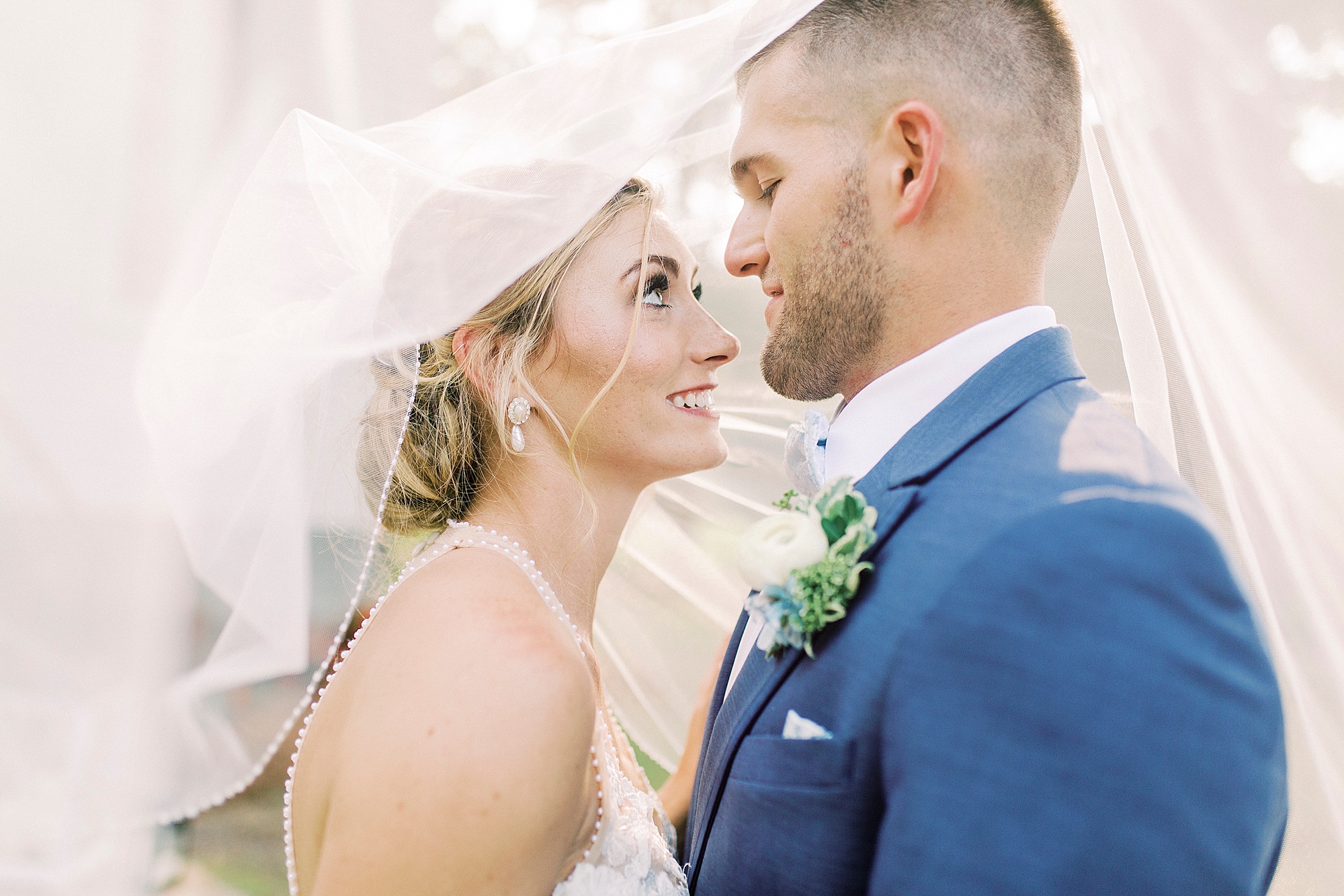 bride and groom look at each other under veil