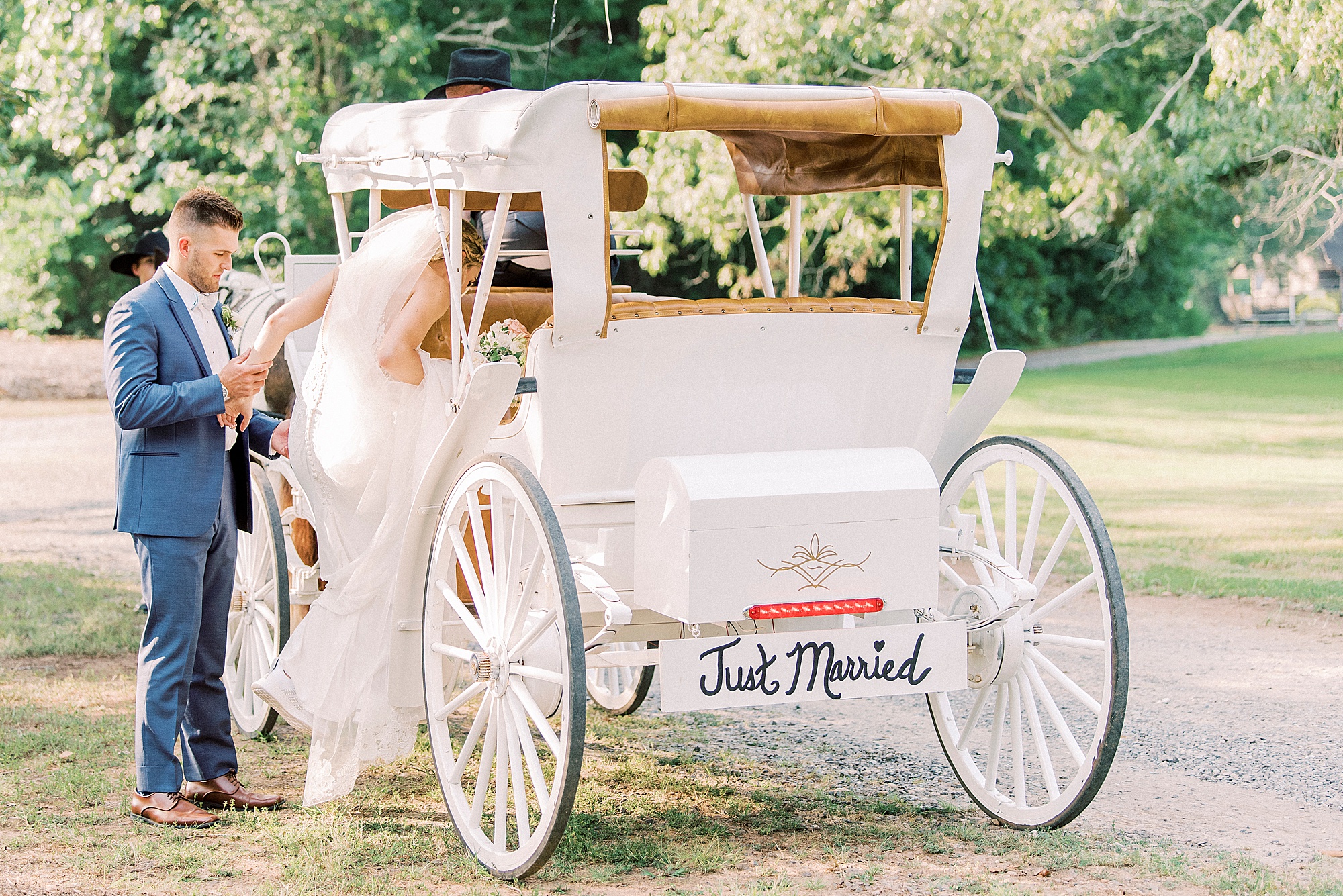 newlyweds pose by white carriage