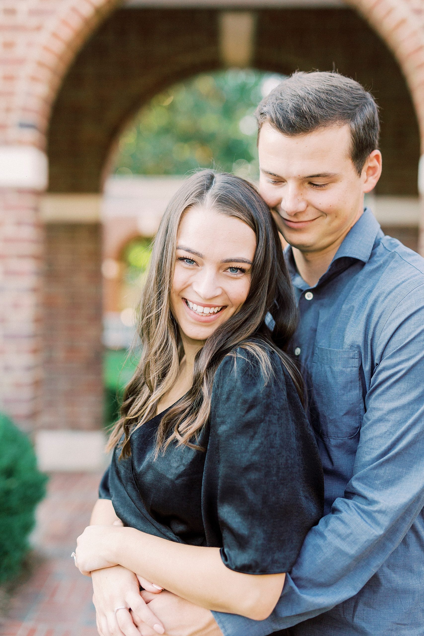 groom hugs bride from behind during engagement photos in Concord NC