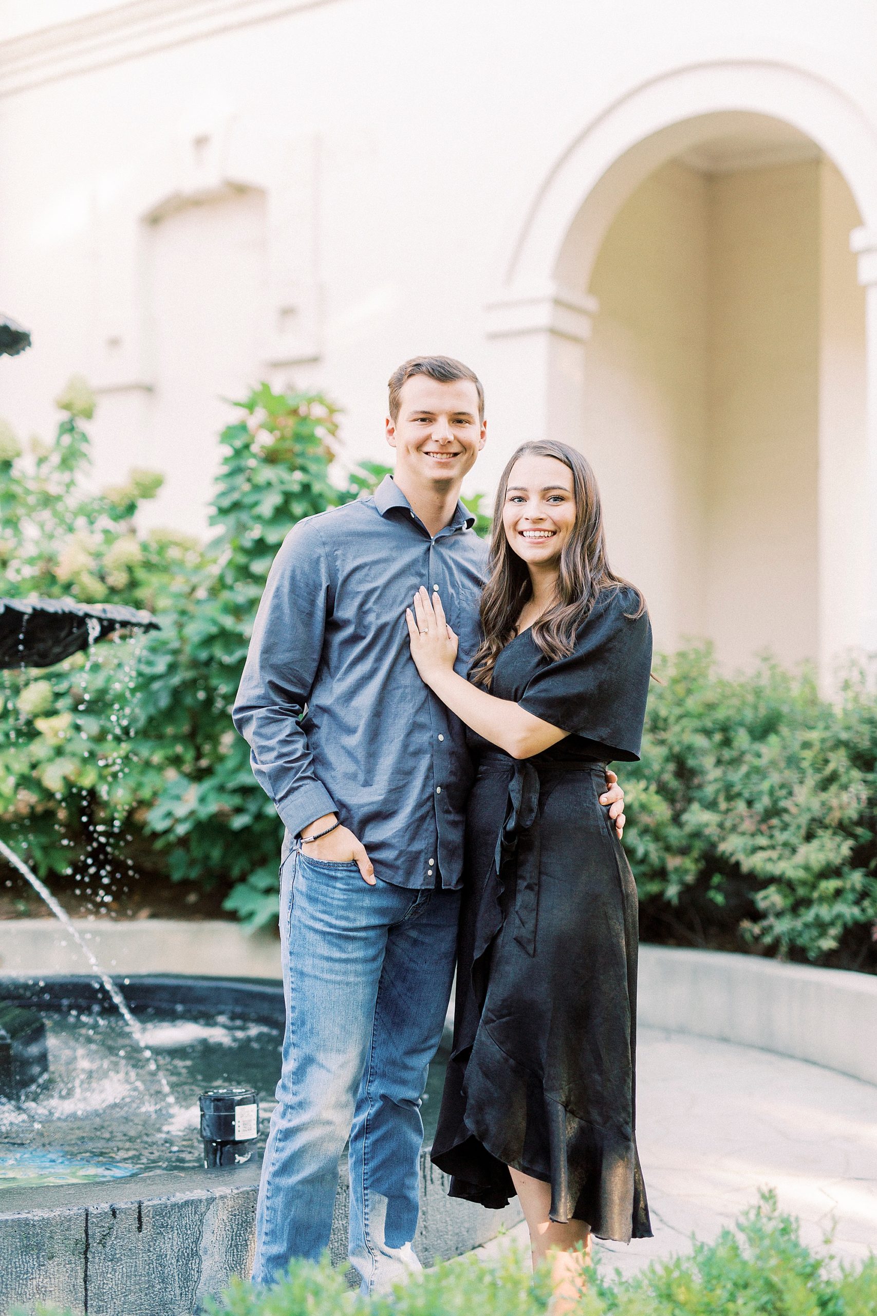 bride and groom stand together by fountain