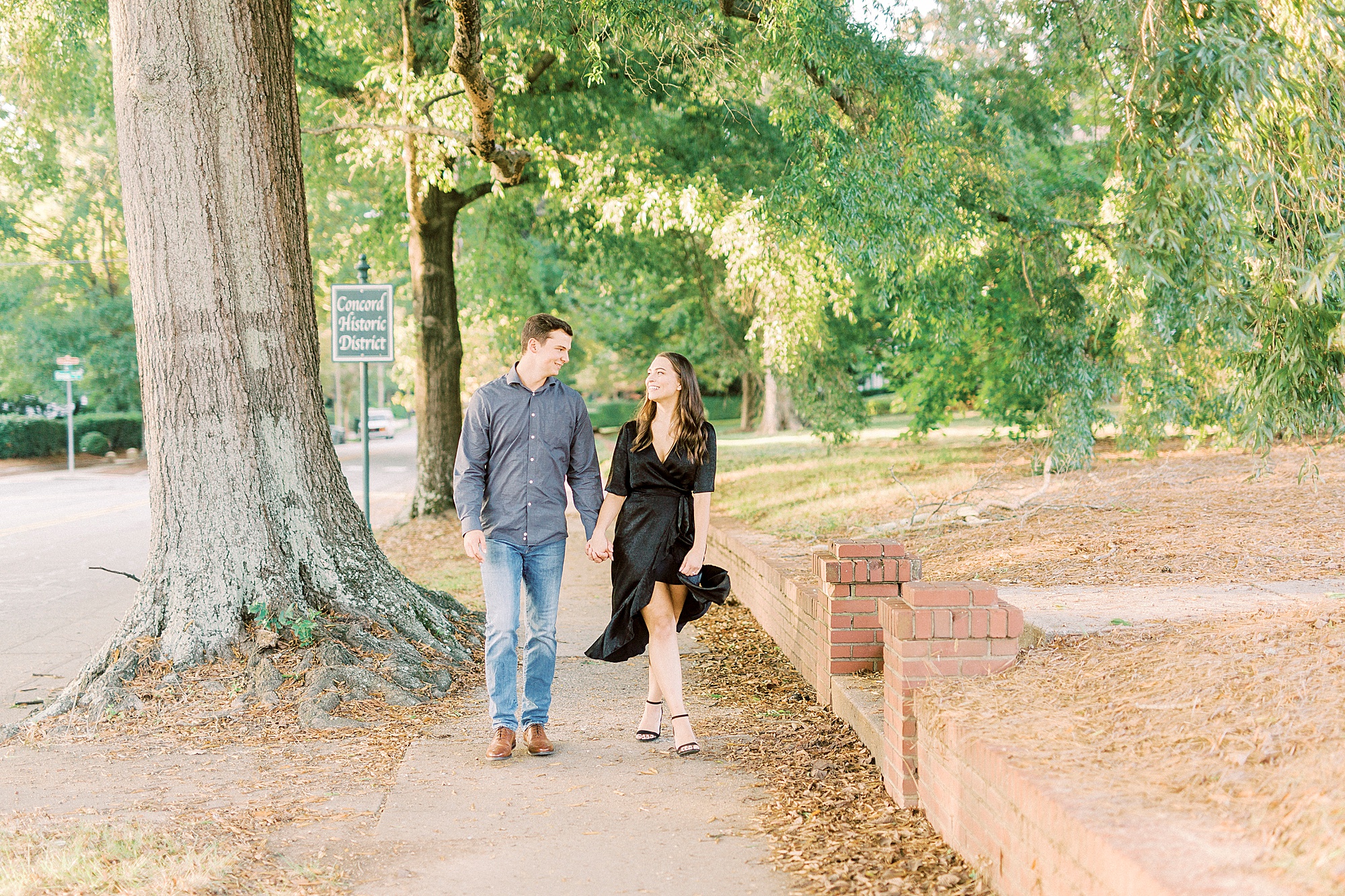 couple holds hands walking through Downtown Concord