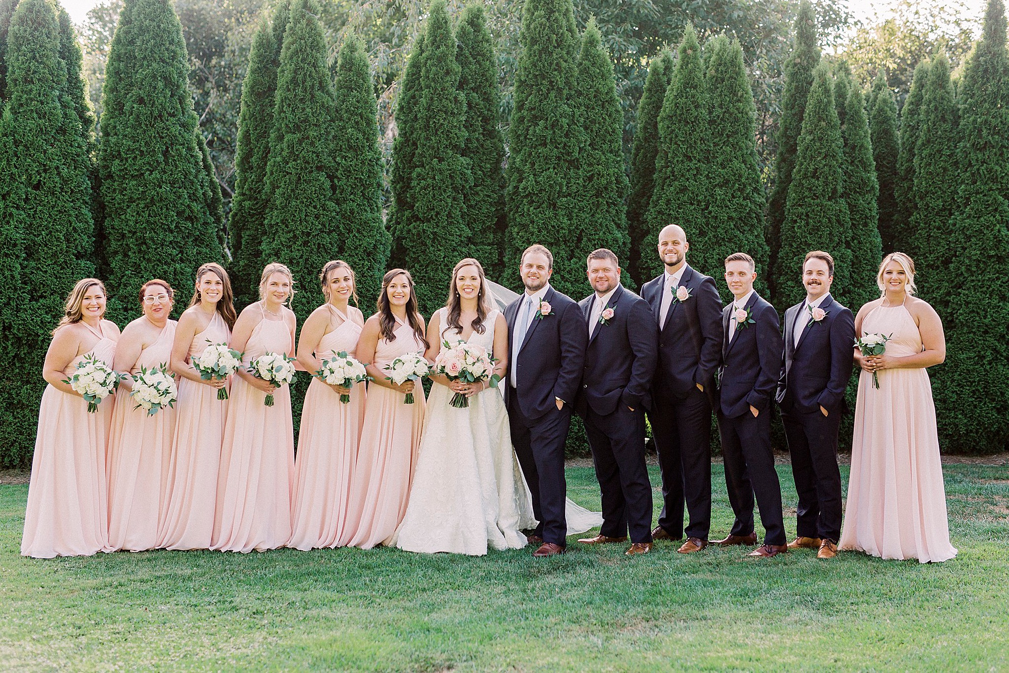bride and groom pose with wedding party in pink and navy