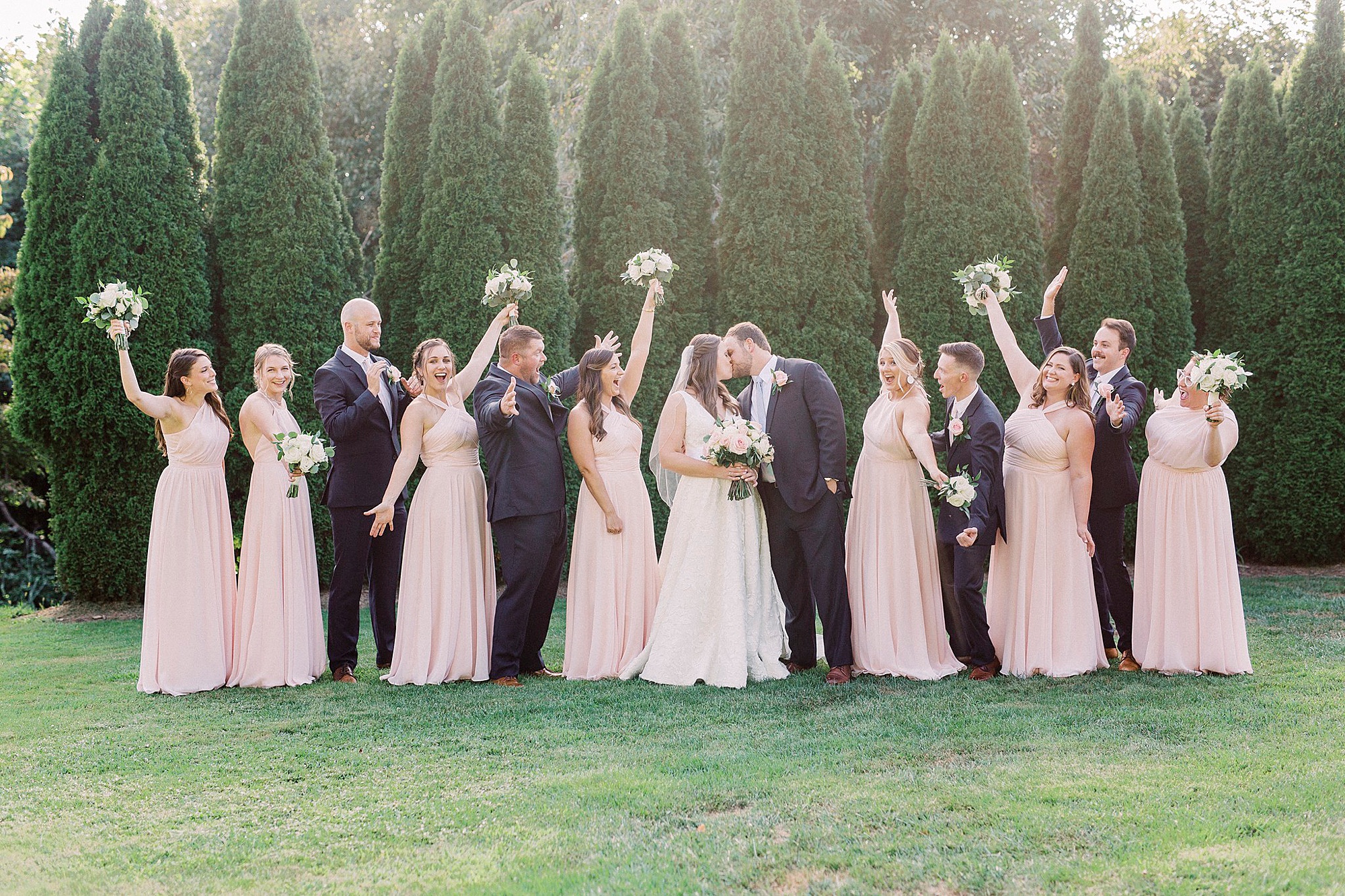 couple kisses while wedding party cheers