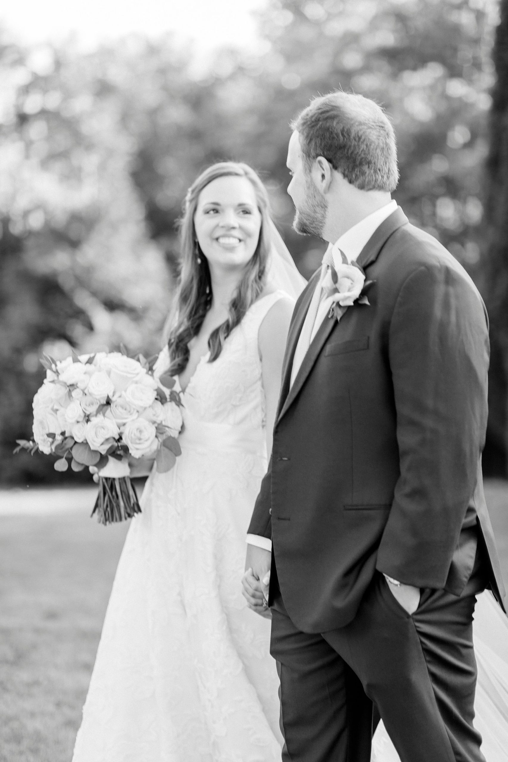 bride looks at groom while walking holding his hand