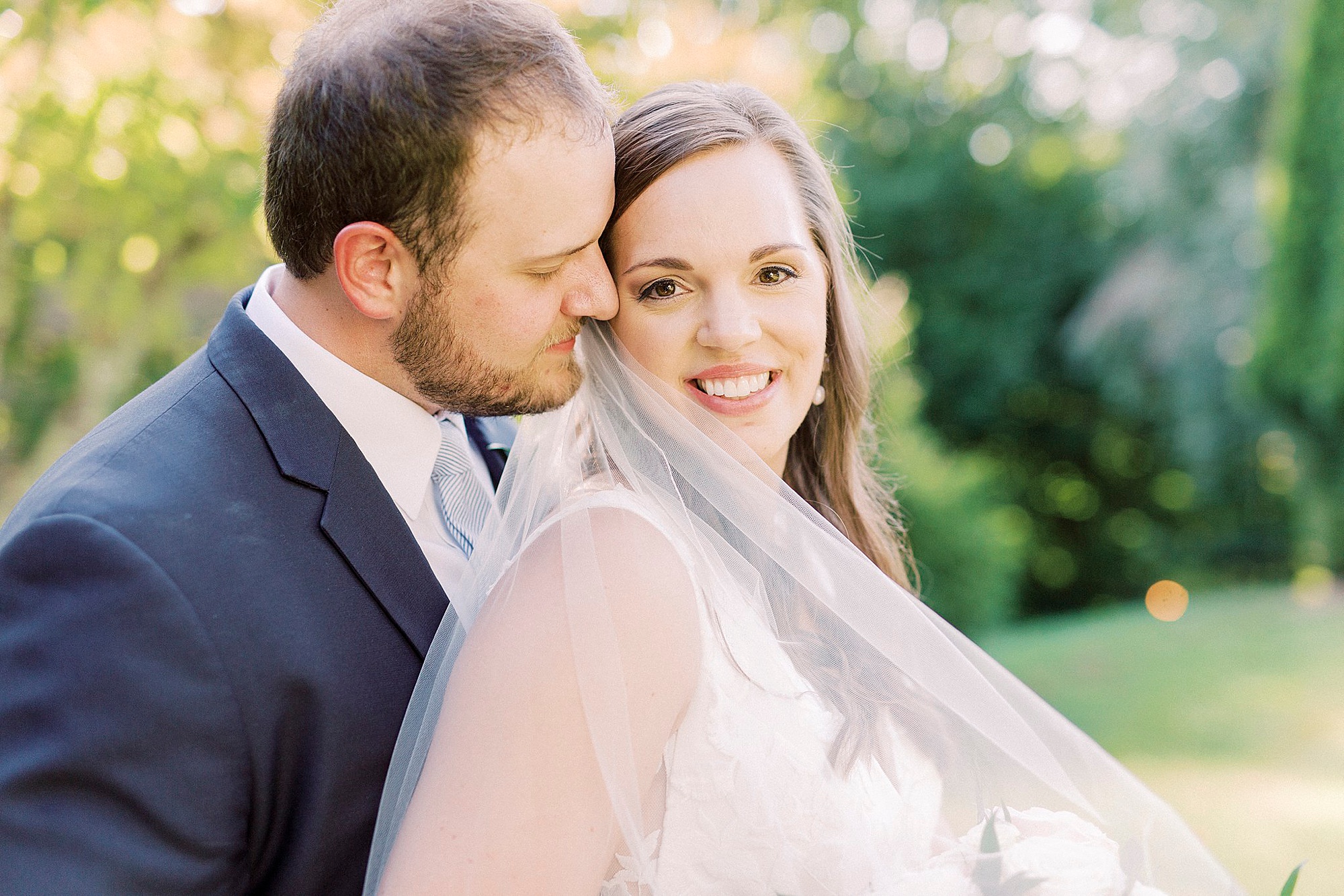 groom hugs bride from behind nuzzling her cheek
