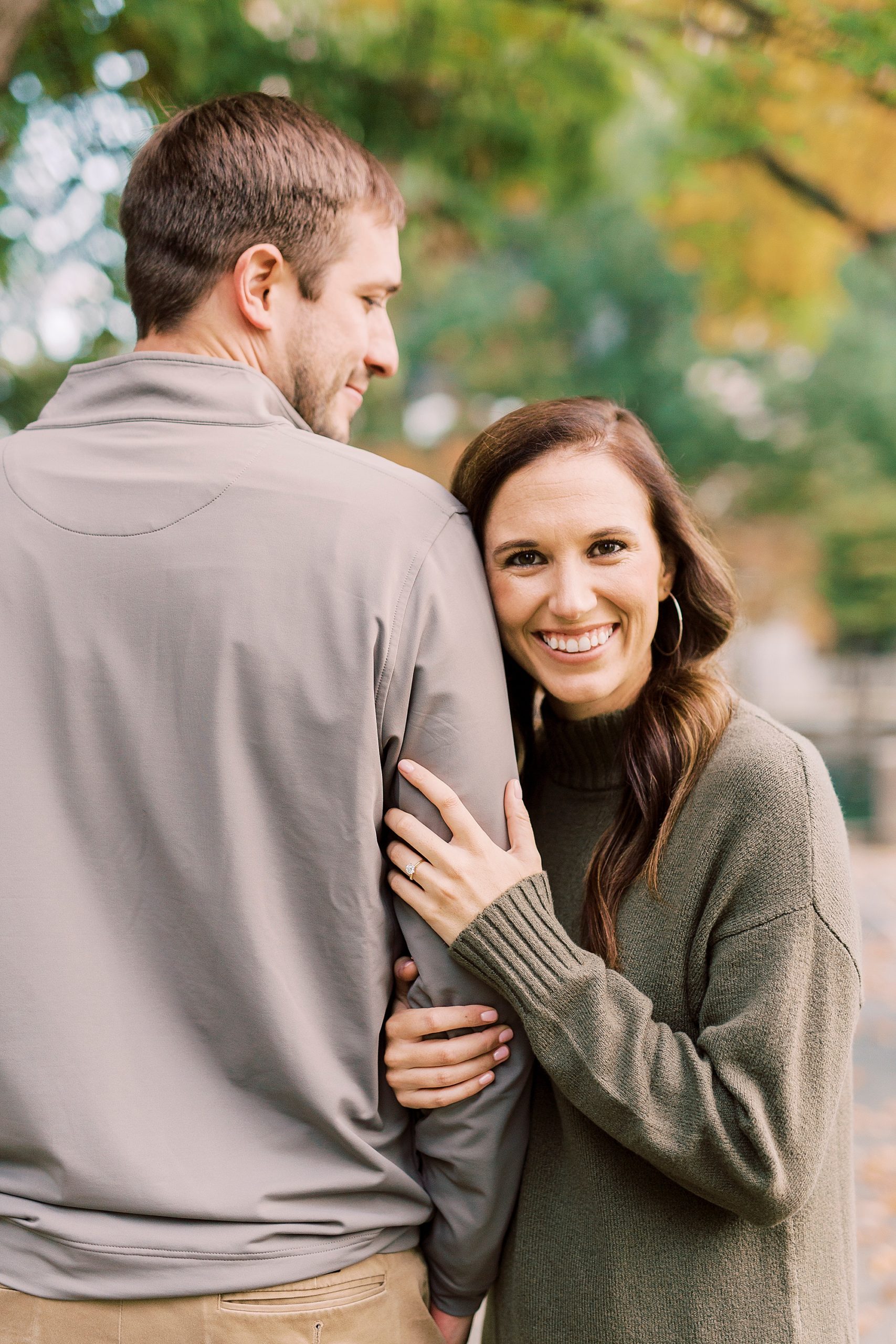 woman leans on fiancé's arm during Marshall Park engagement session