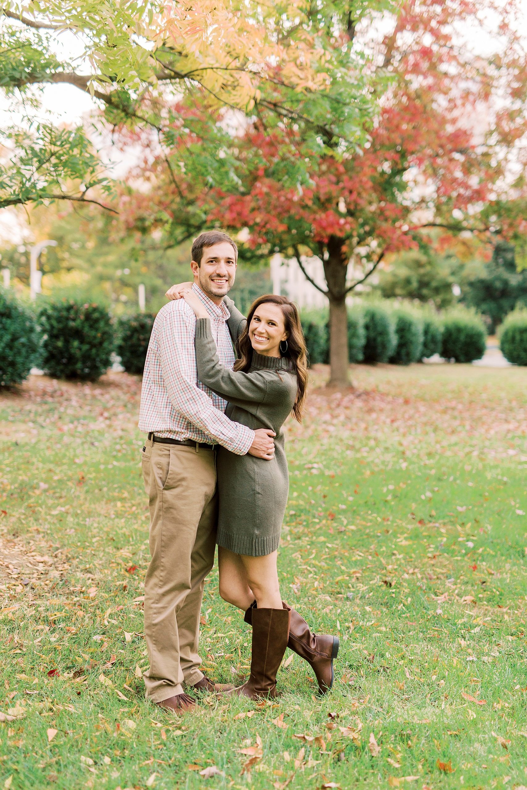 couple hugs in park with fall leaves around them