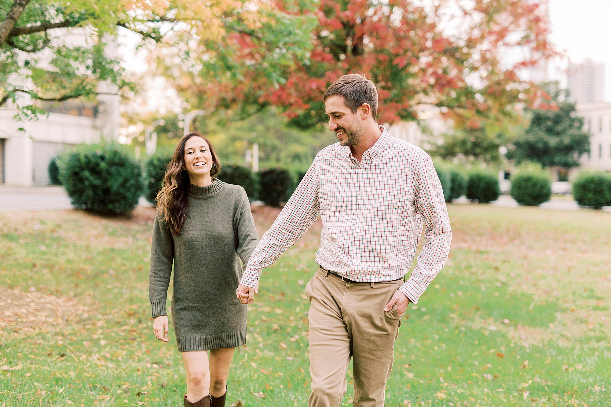 engaged couple holds hands walking through the park in Charlotte NC