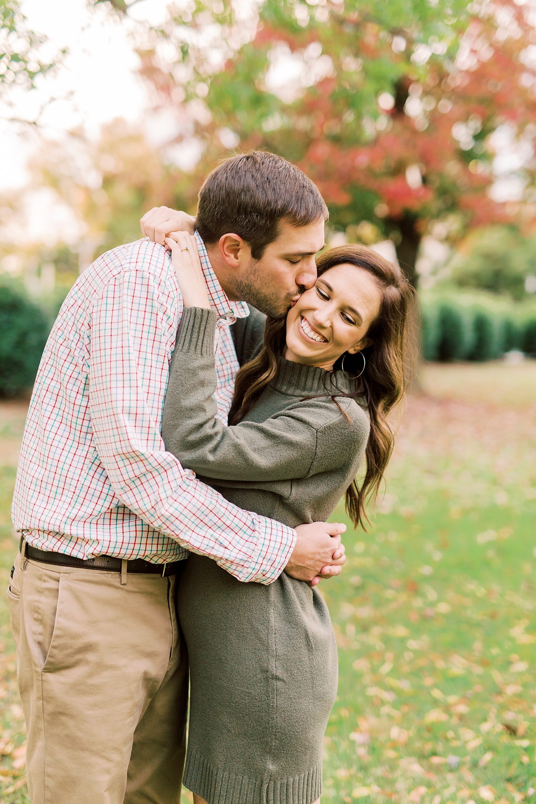 groom leans to kiss fiancee during Marshall Park engagement session