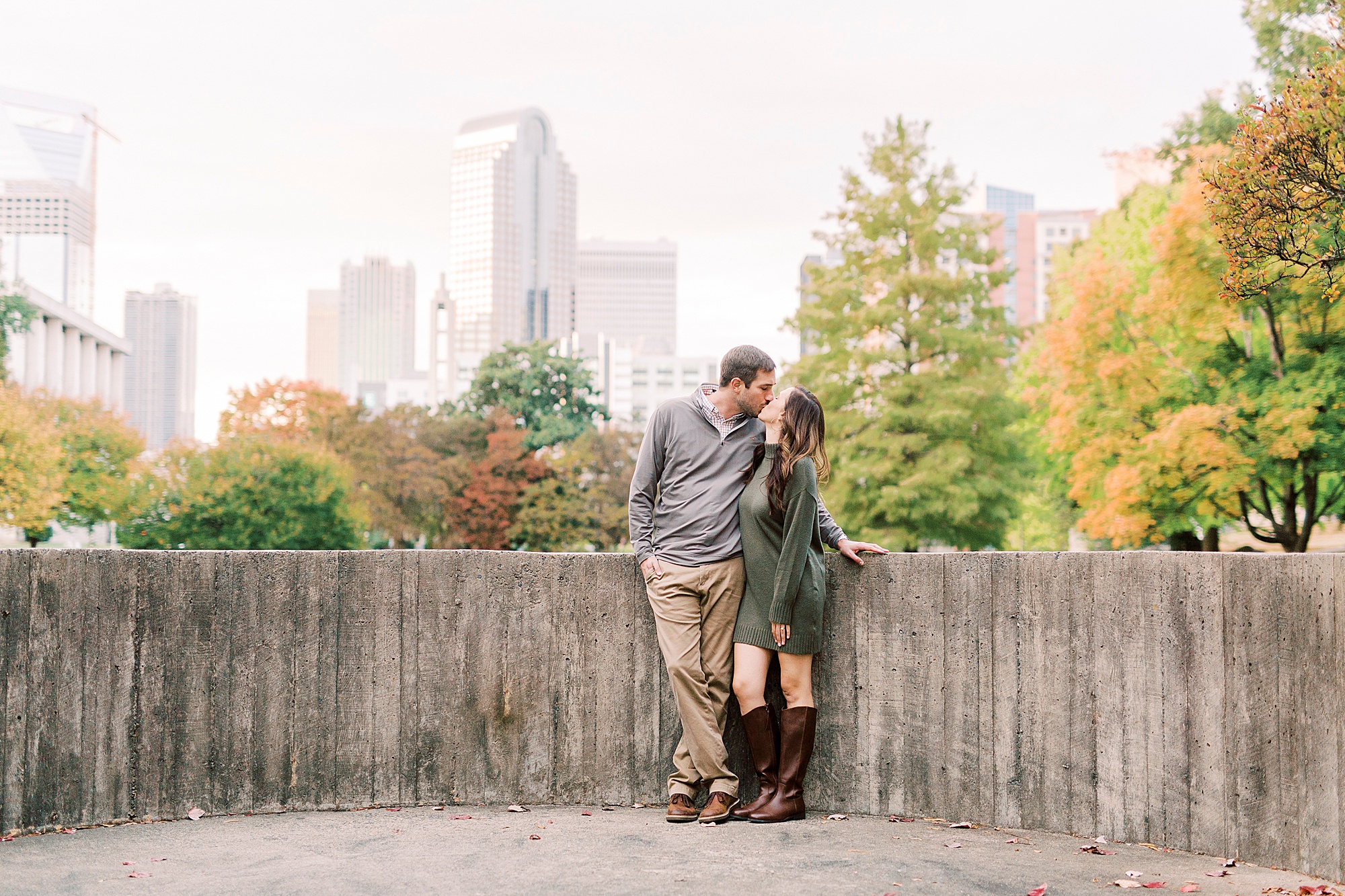 couple kisses along wall during Marshall Park engagement session