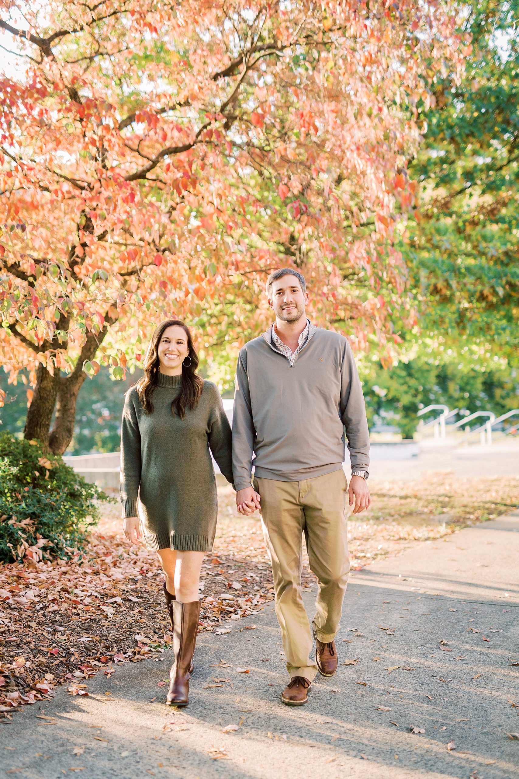 couple holds hands walking through Charlotte park