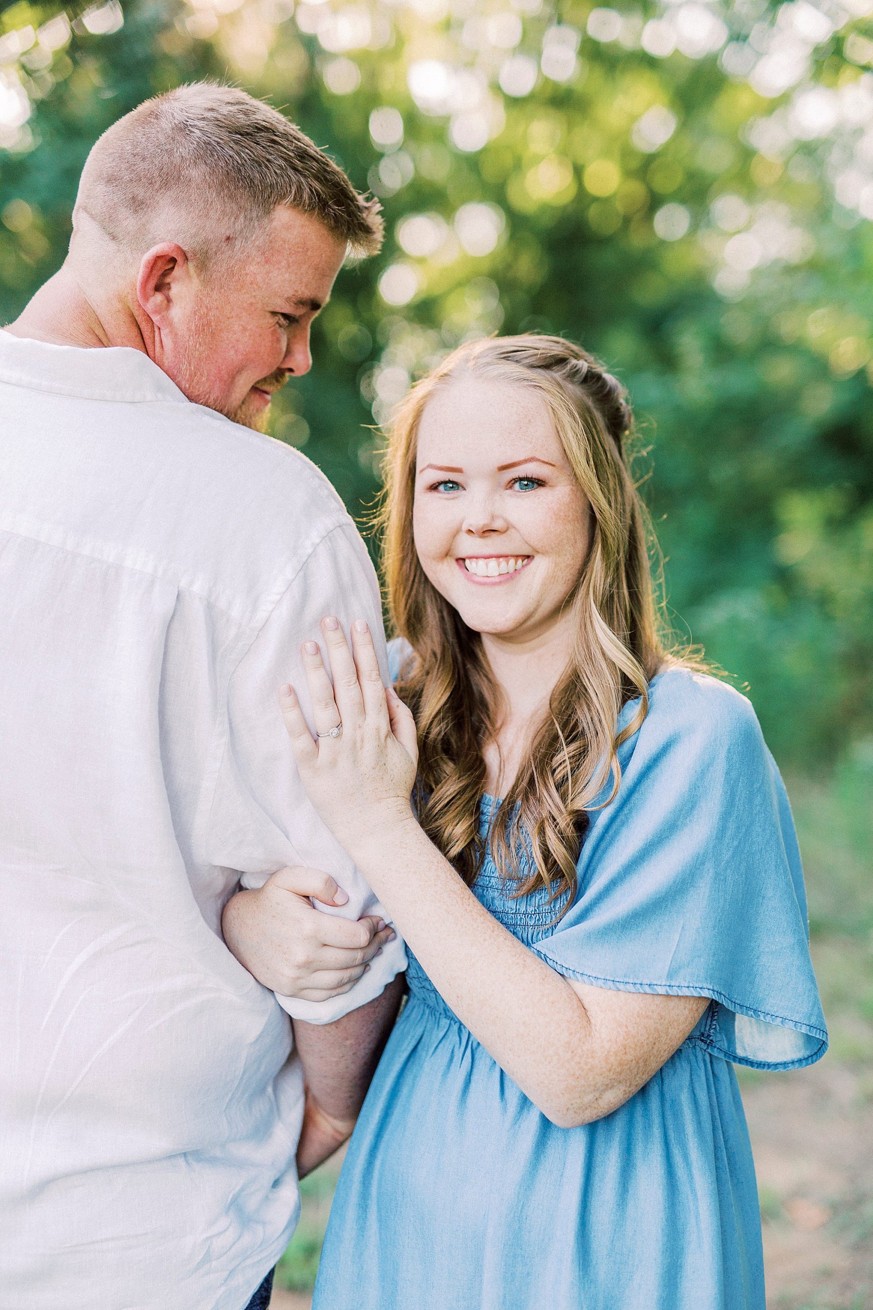 bride holds groom's arm showing off engagement ring