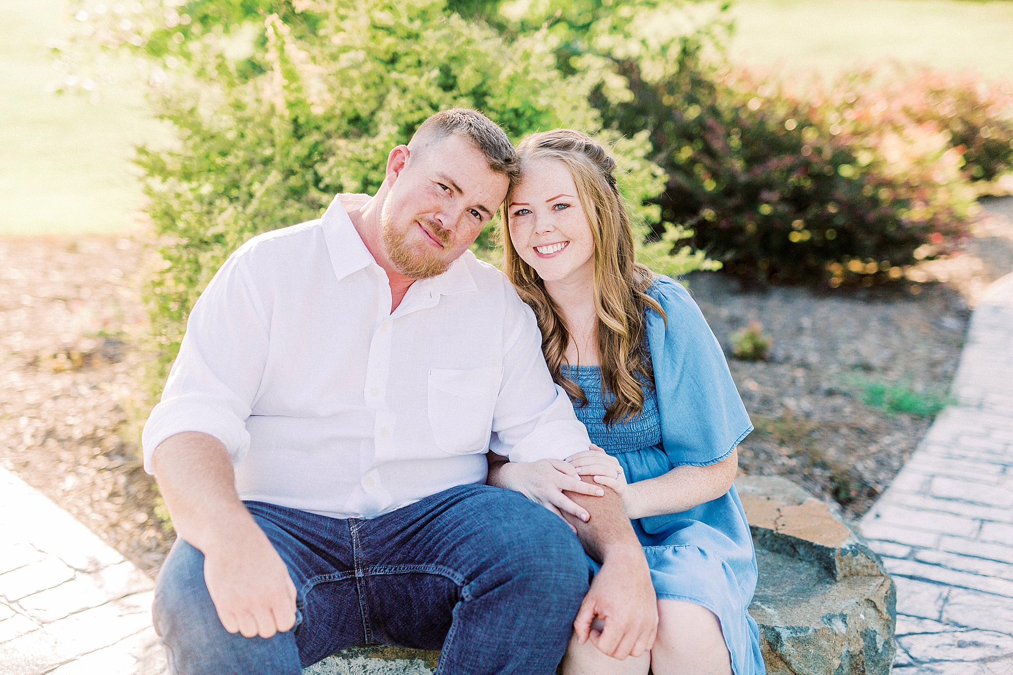 bride and groom sit on rocks during Sunset Farm engagement session
