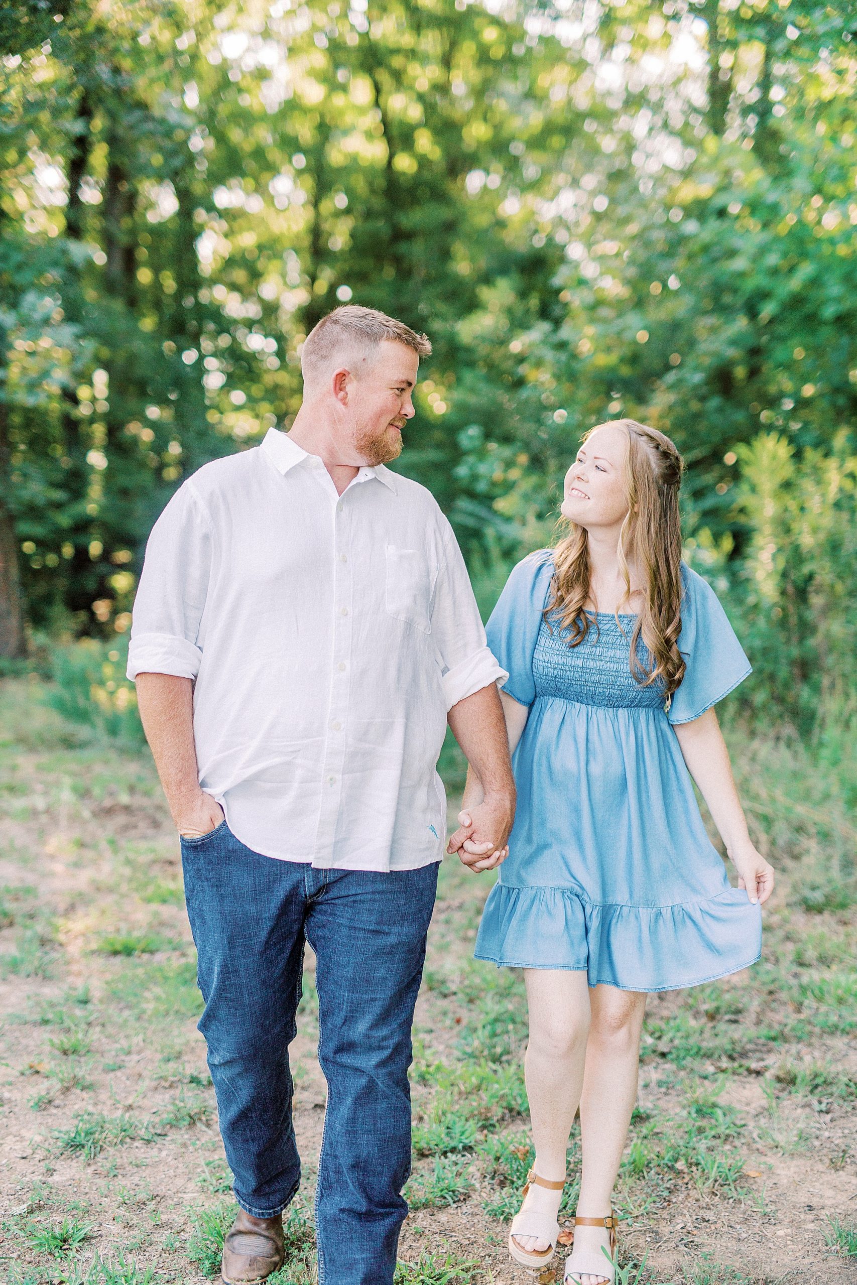 engaged couple walks through trees