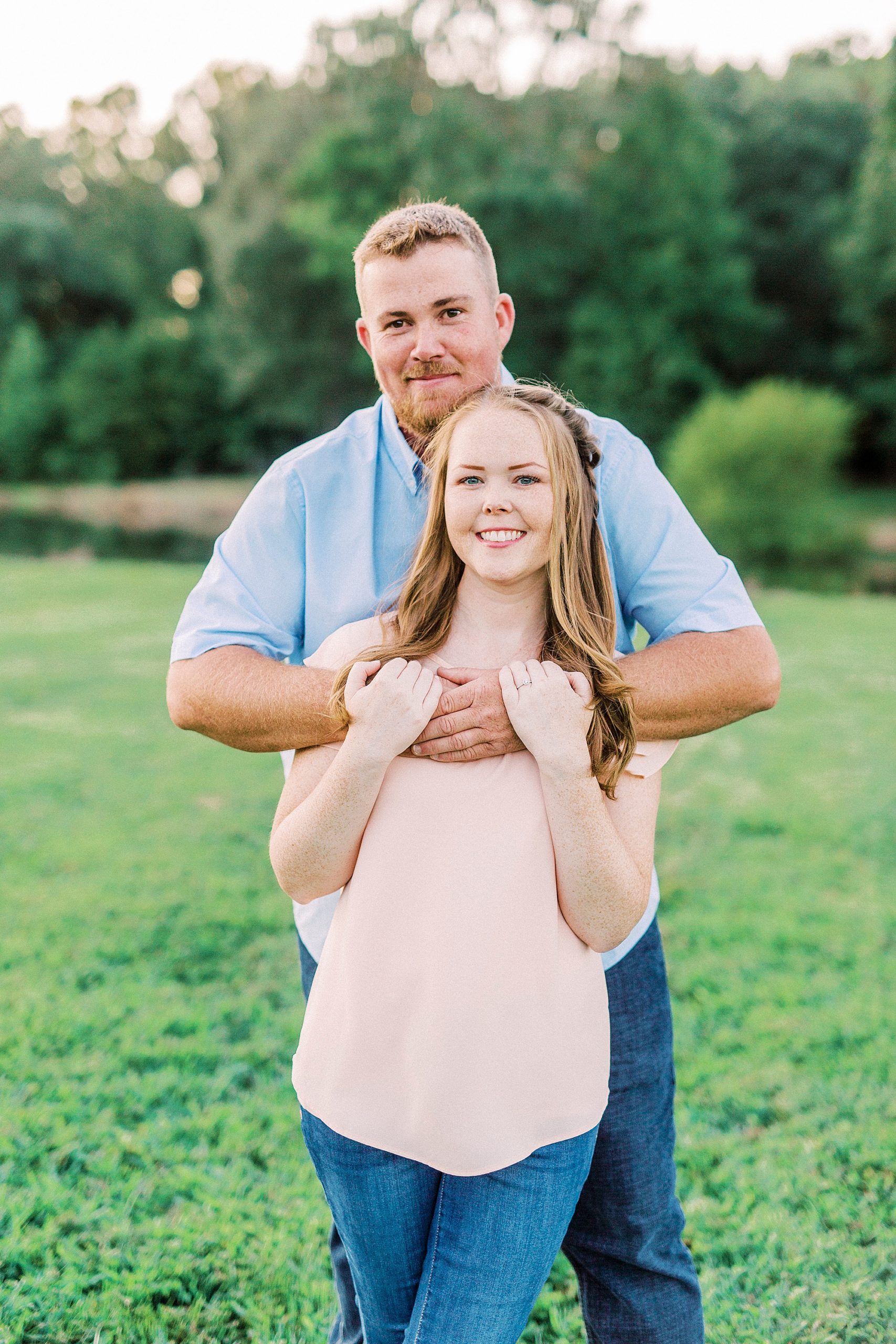 groom hugs bride from behind during NC engagement photos on farm