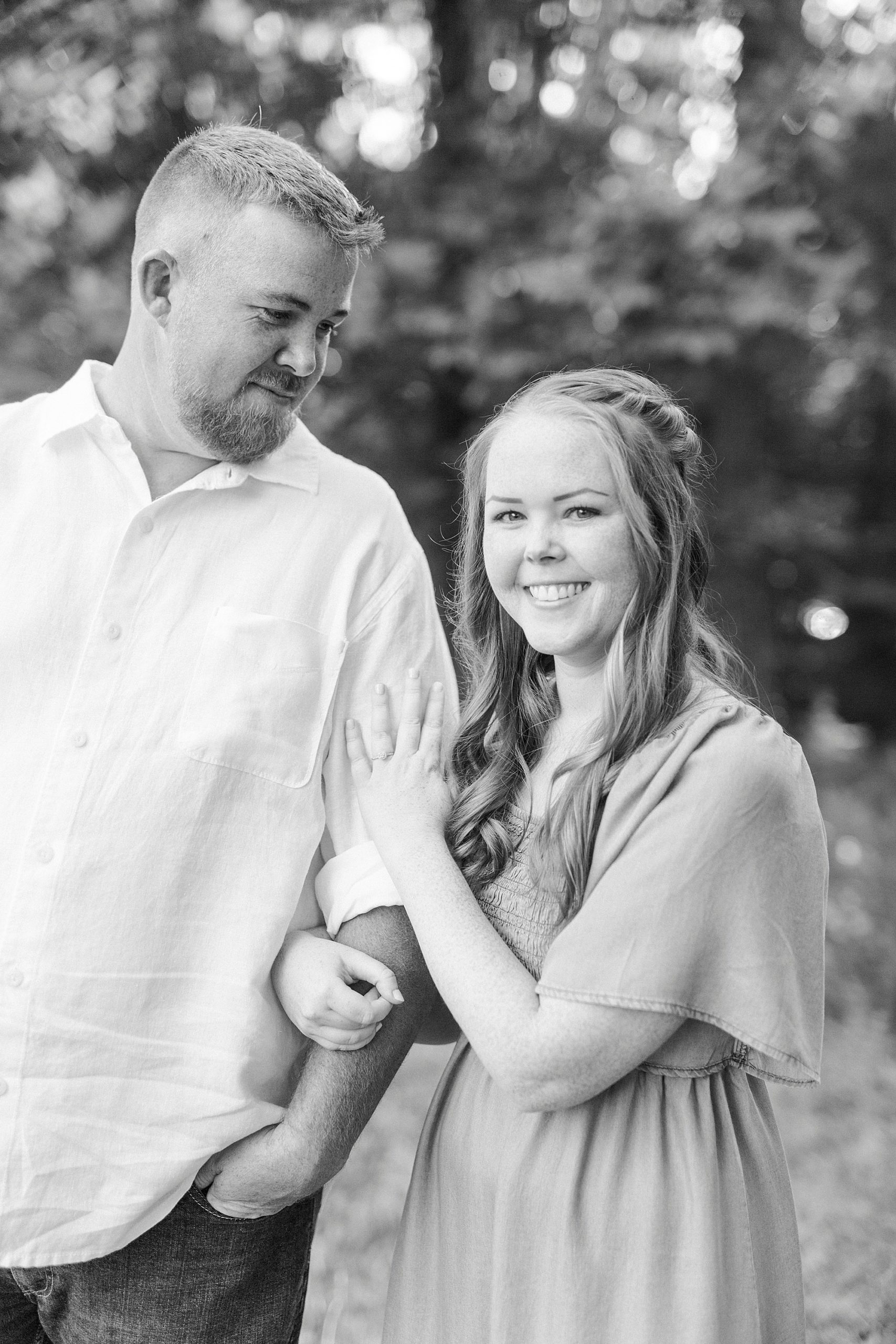 bride holds groom's arm during Concord NC engagement photos