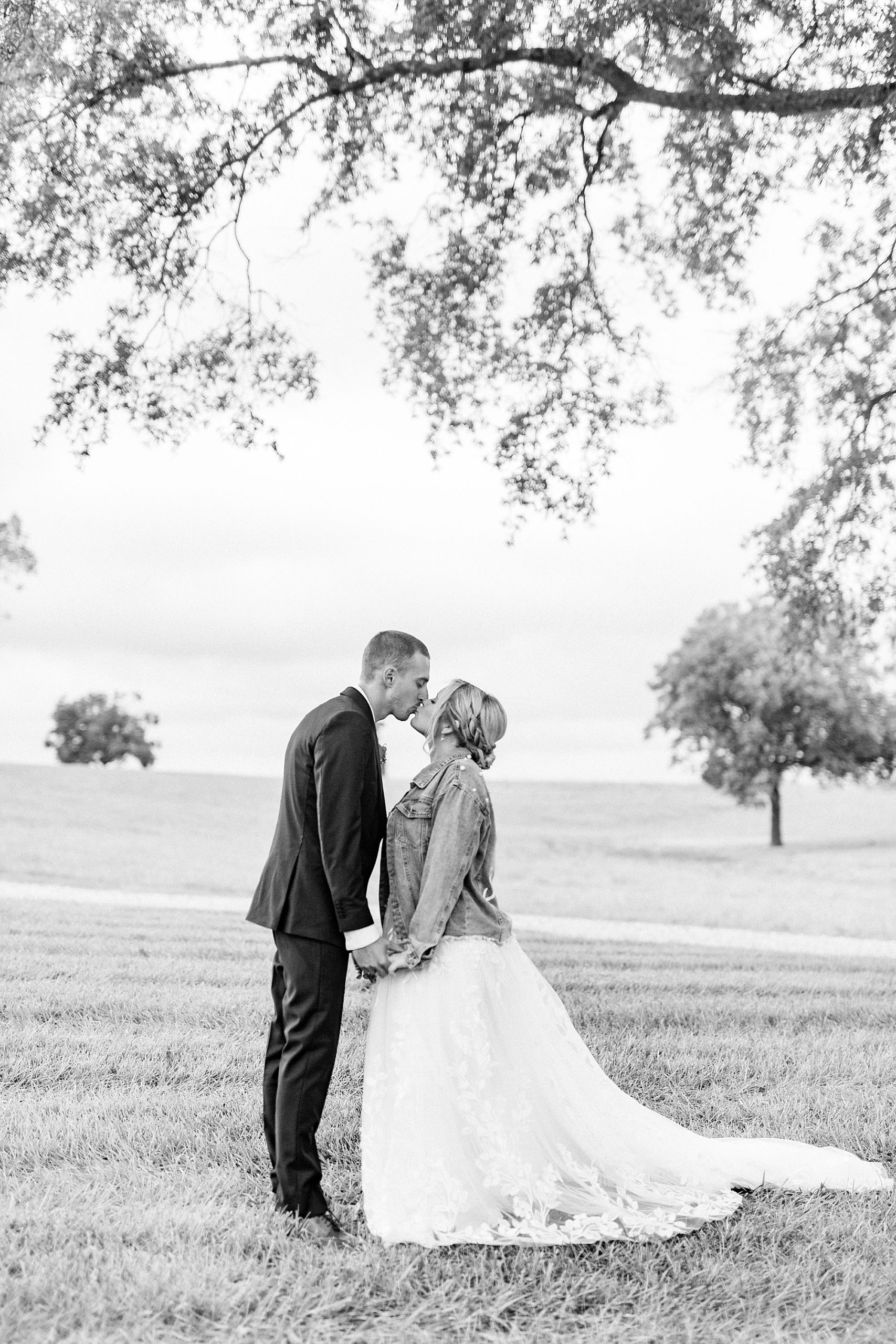newlyweds kiss while bride's wearing jean jacket