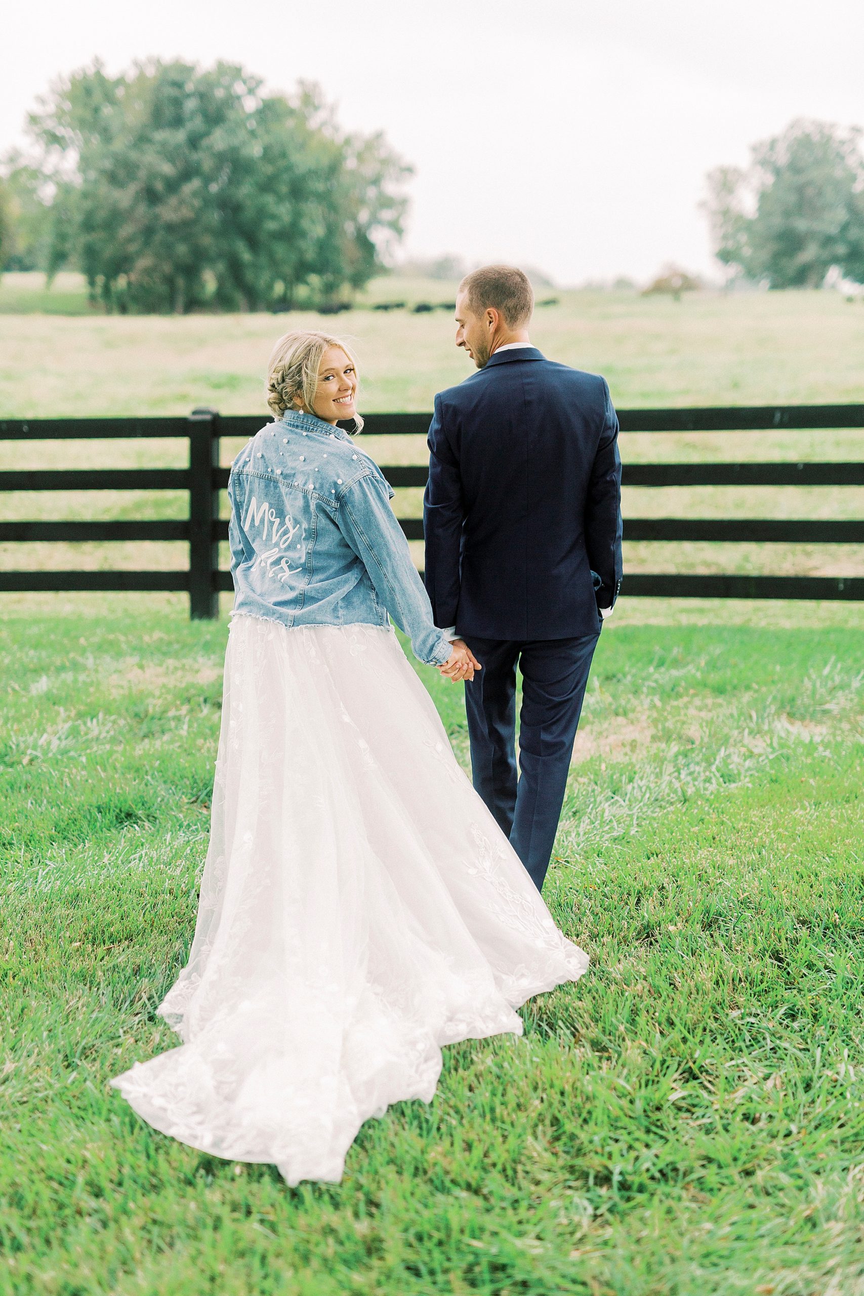 bride walks wearing jean jacket during portraits at Addison Farm