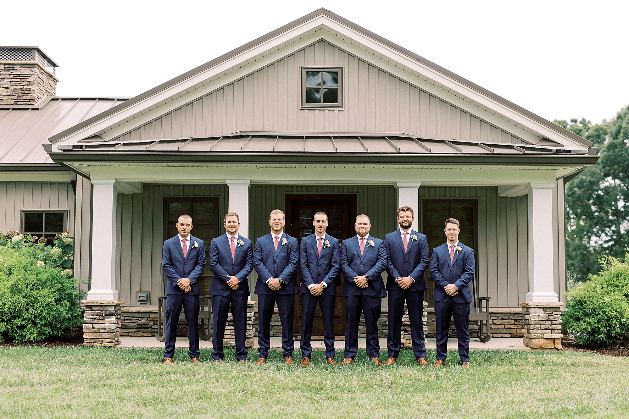 groom and groomsmen pose outside farmhouse at Addison Farm