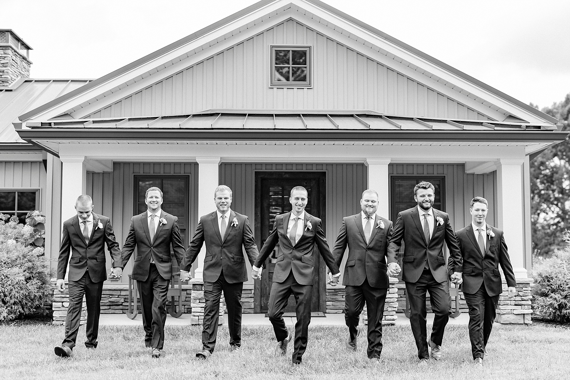 groom and groomsmen walk outside Addison Farm building