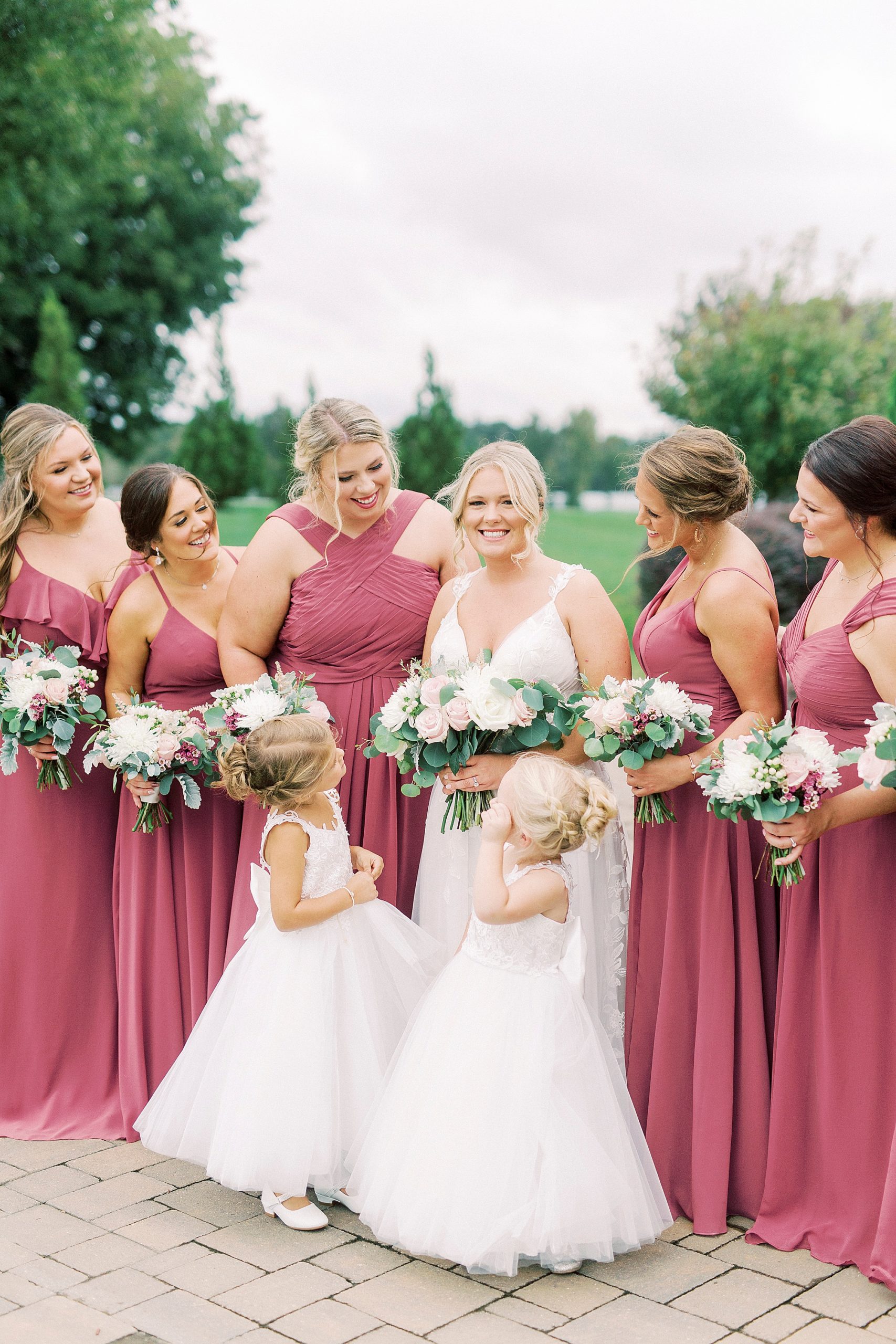 bridesmaids in dark pink laugh with bride