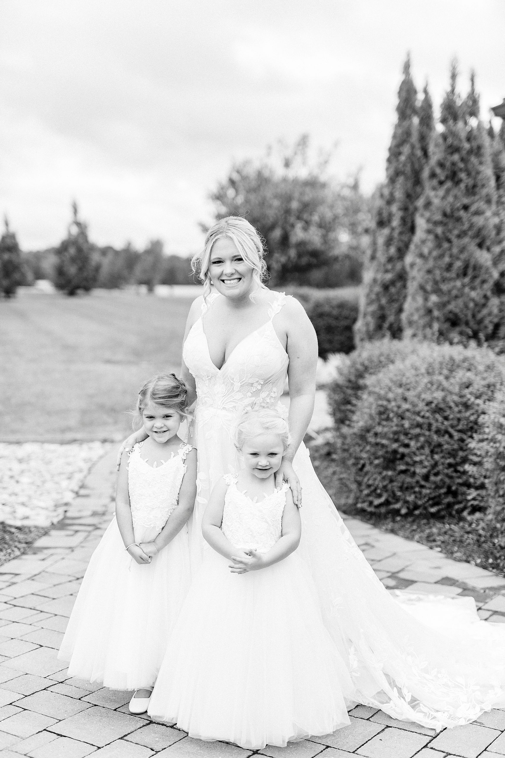 bride poses with two flower girls on wedding day