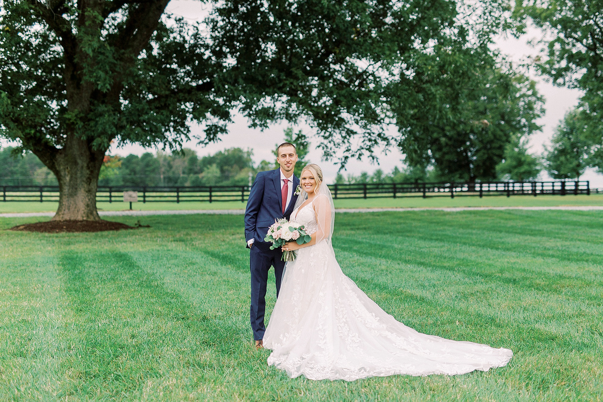 bride and groom stand together under tree in Greensboro NC