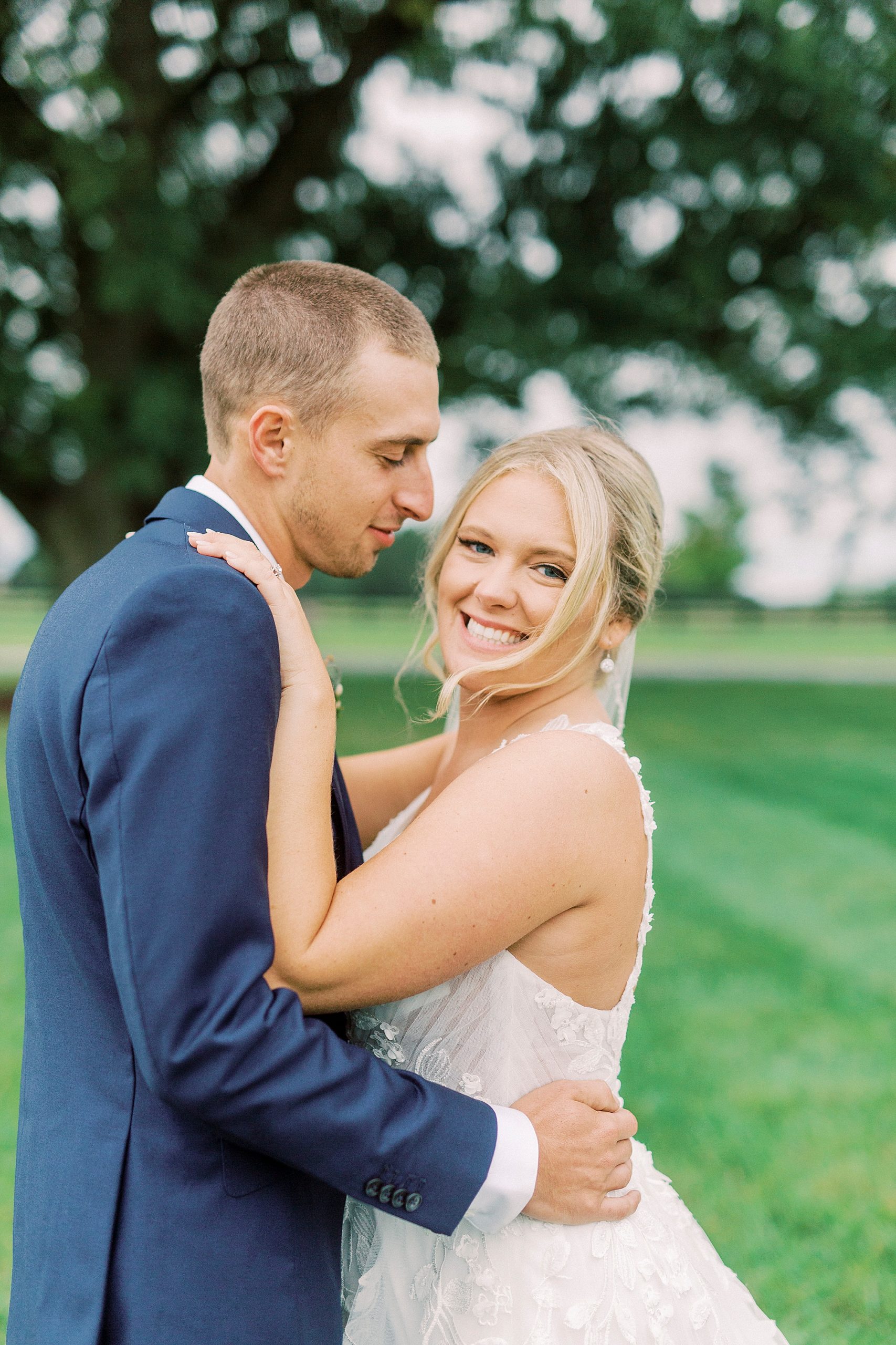 bride and groom hug by tree at Addison Farm