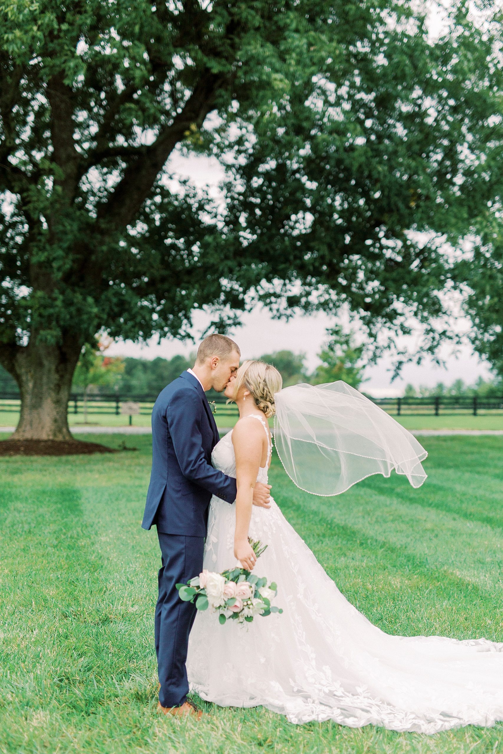 newlyweds pose with bride's veil floating behind them