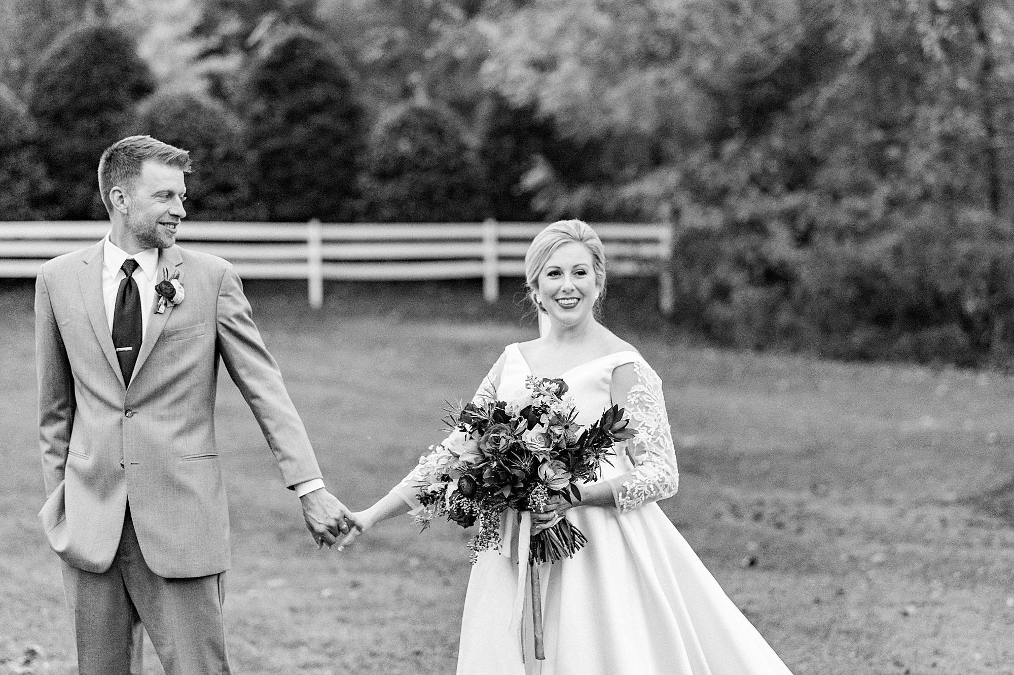 couple holds hands walking through yard at Vesuvius Vineyards