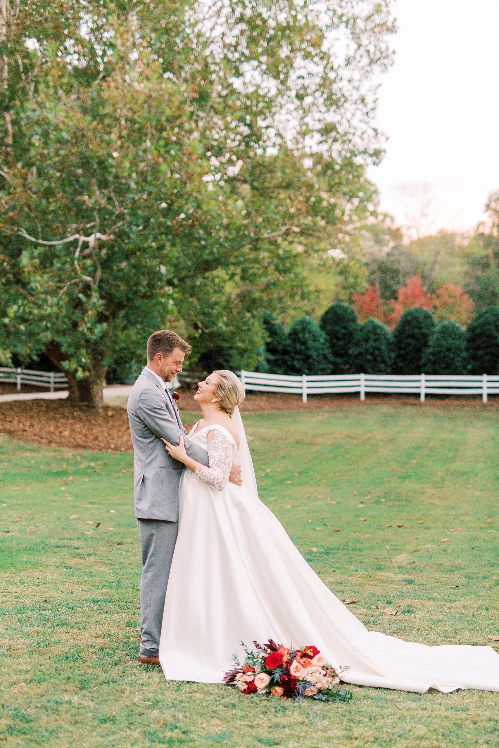 bride and groom stand together with bouquet by bride's skirt