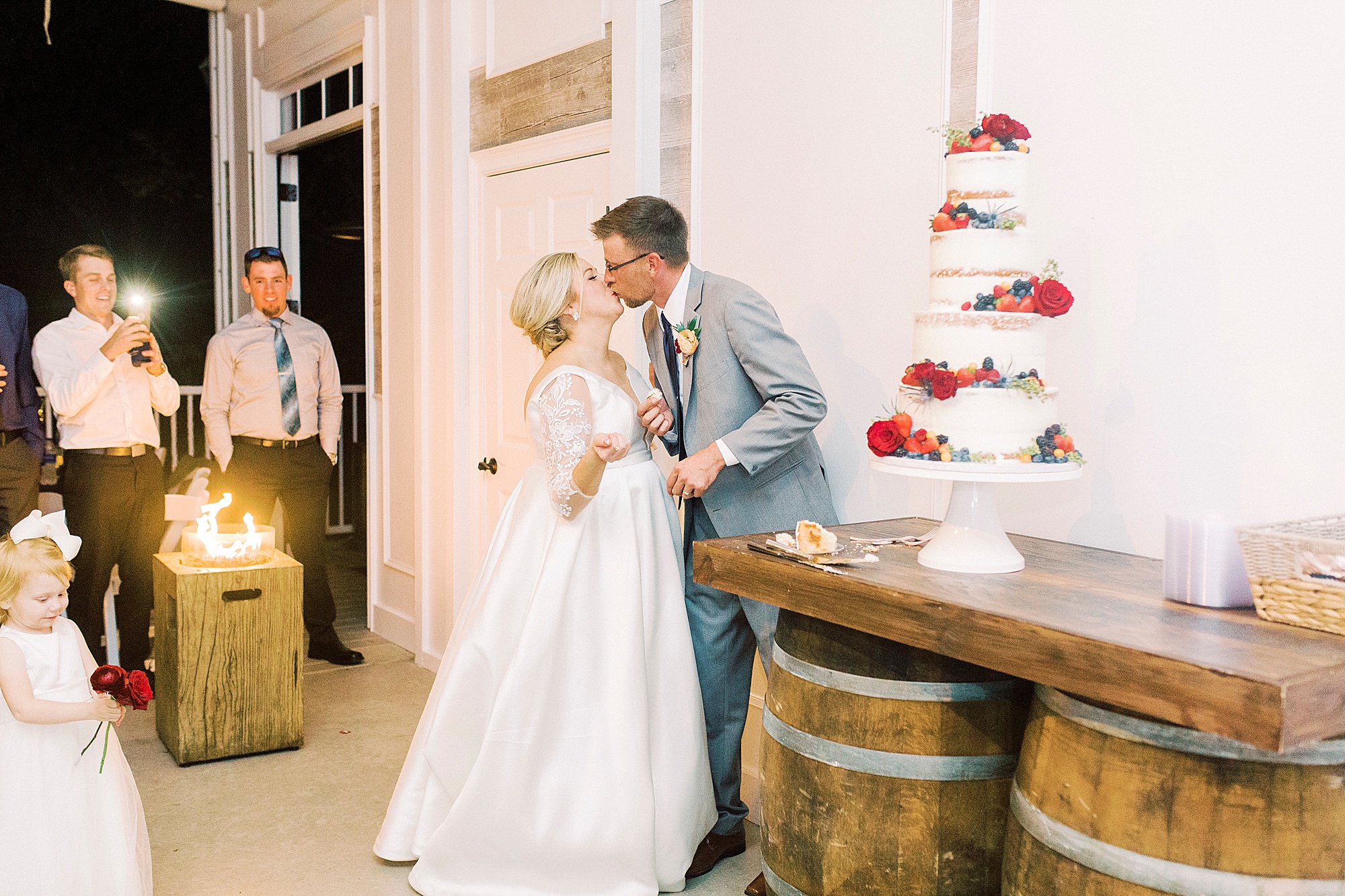 couple kisses during cake cutting during NC wedding reception