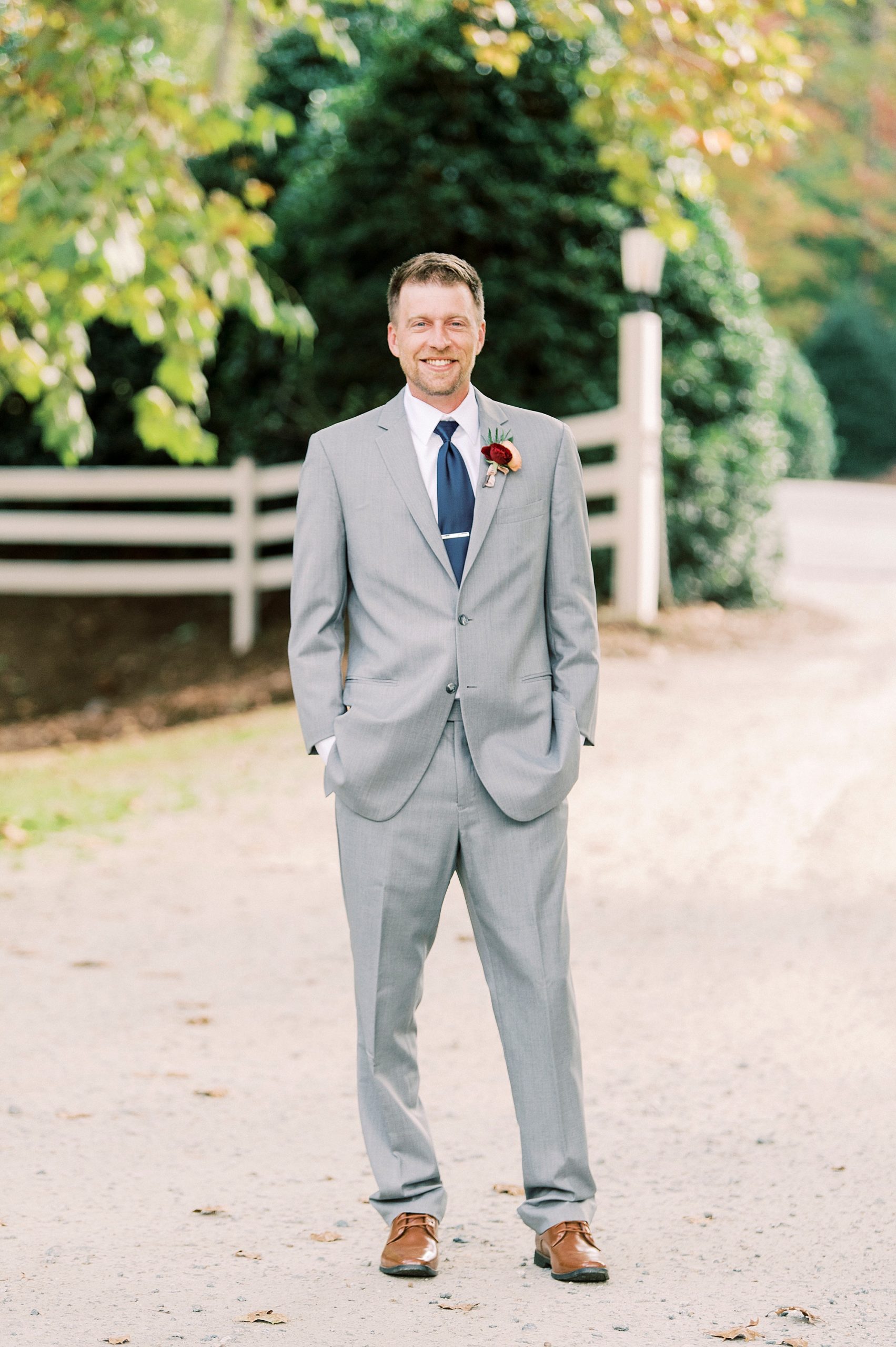 groom poses in grey suit with navy tie for Vesuvius Vineyards wedding day