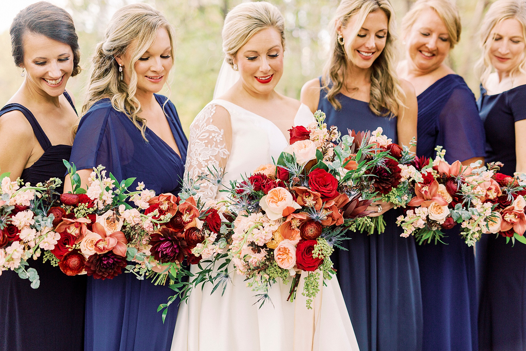 bride looks down at bouquet of red flowers
