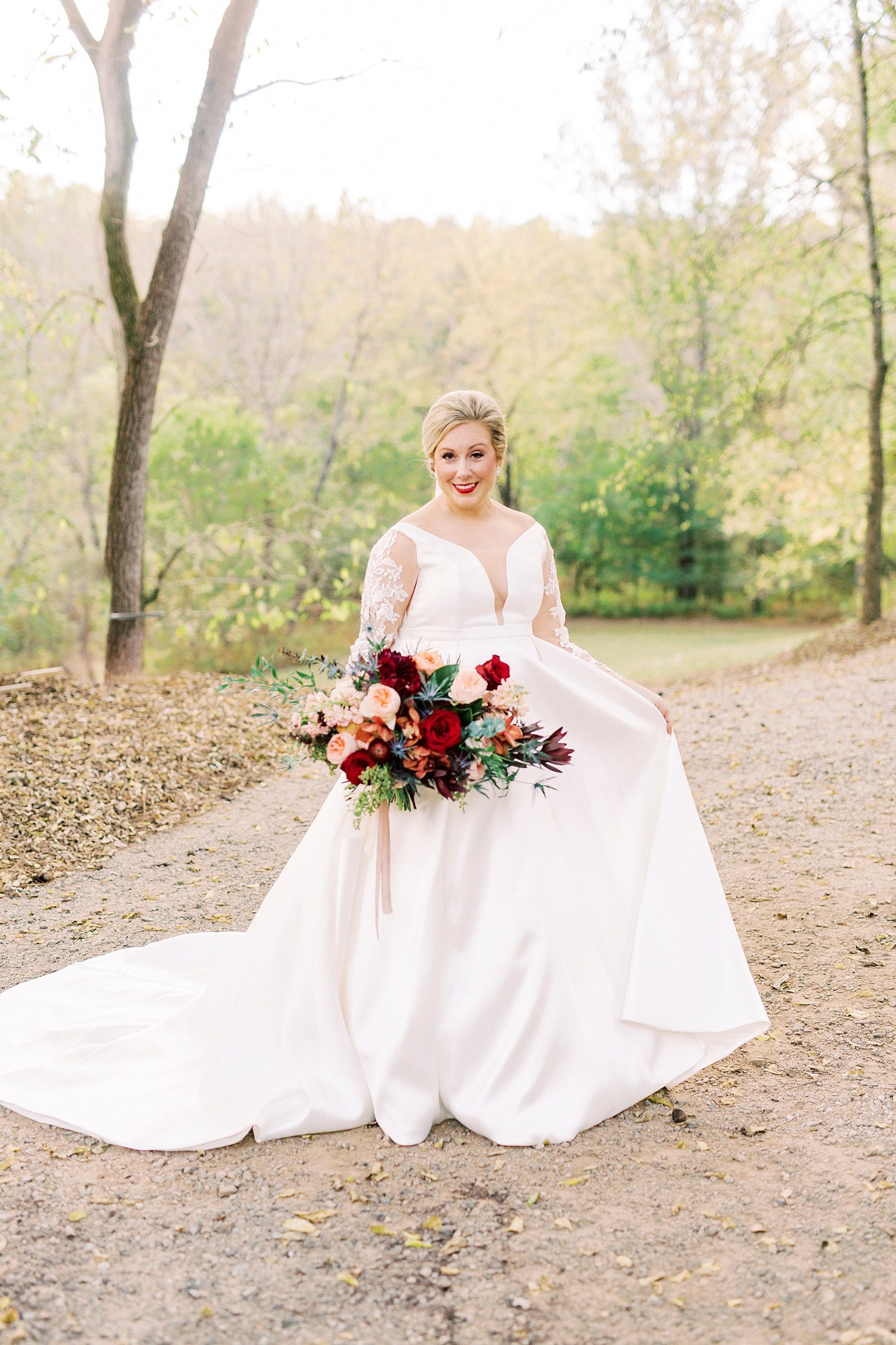 fall bride holds bouquet of pink and red flowers