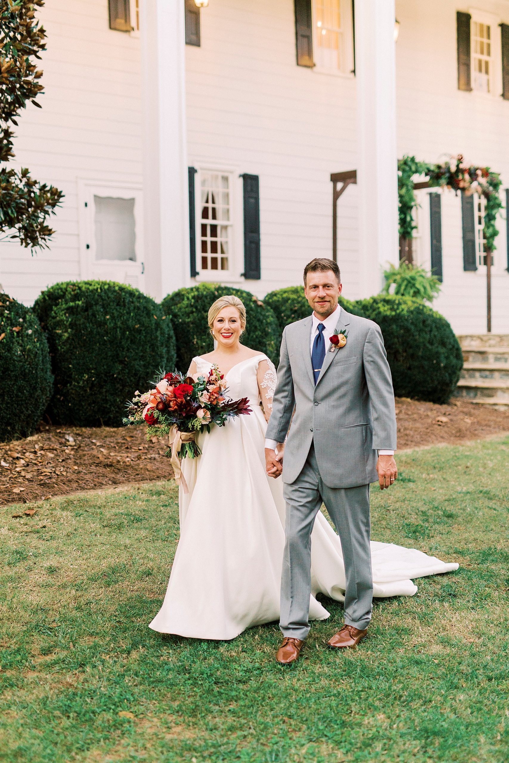 bride and groom hold hands walking by manor house at Vesuvius Vineyards
