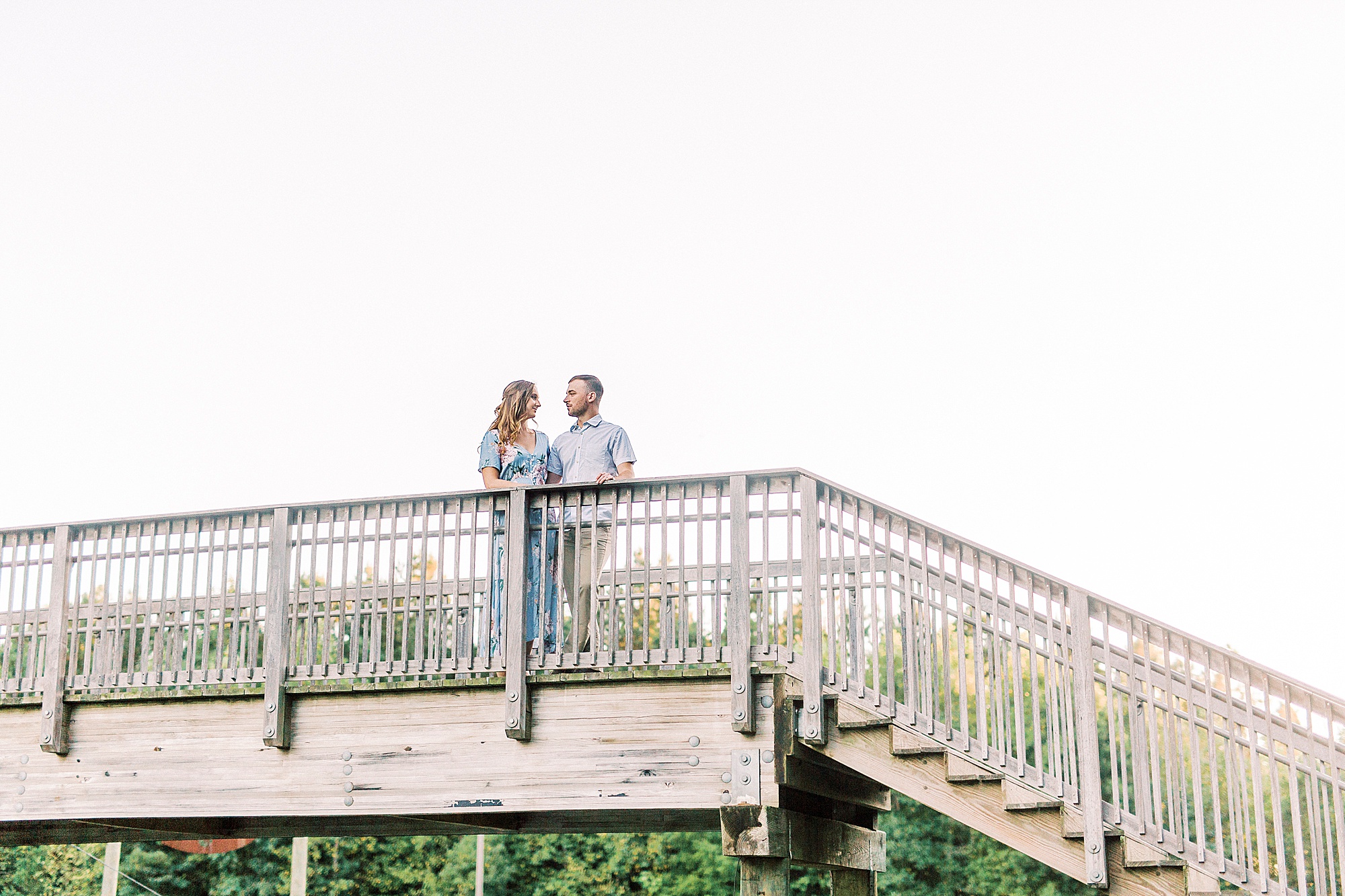 couple stands on wooden bridge at the Whitewater Center