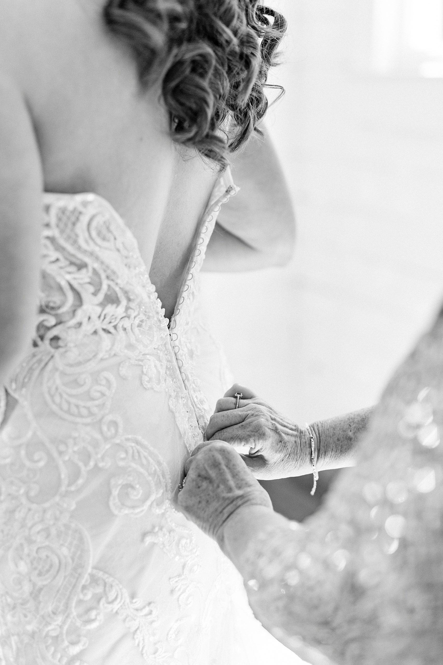 mother helps bride with wedding gown