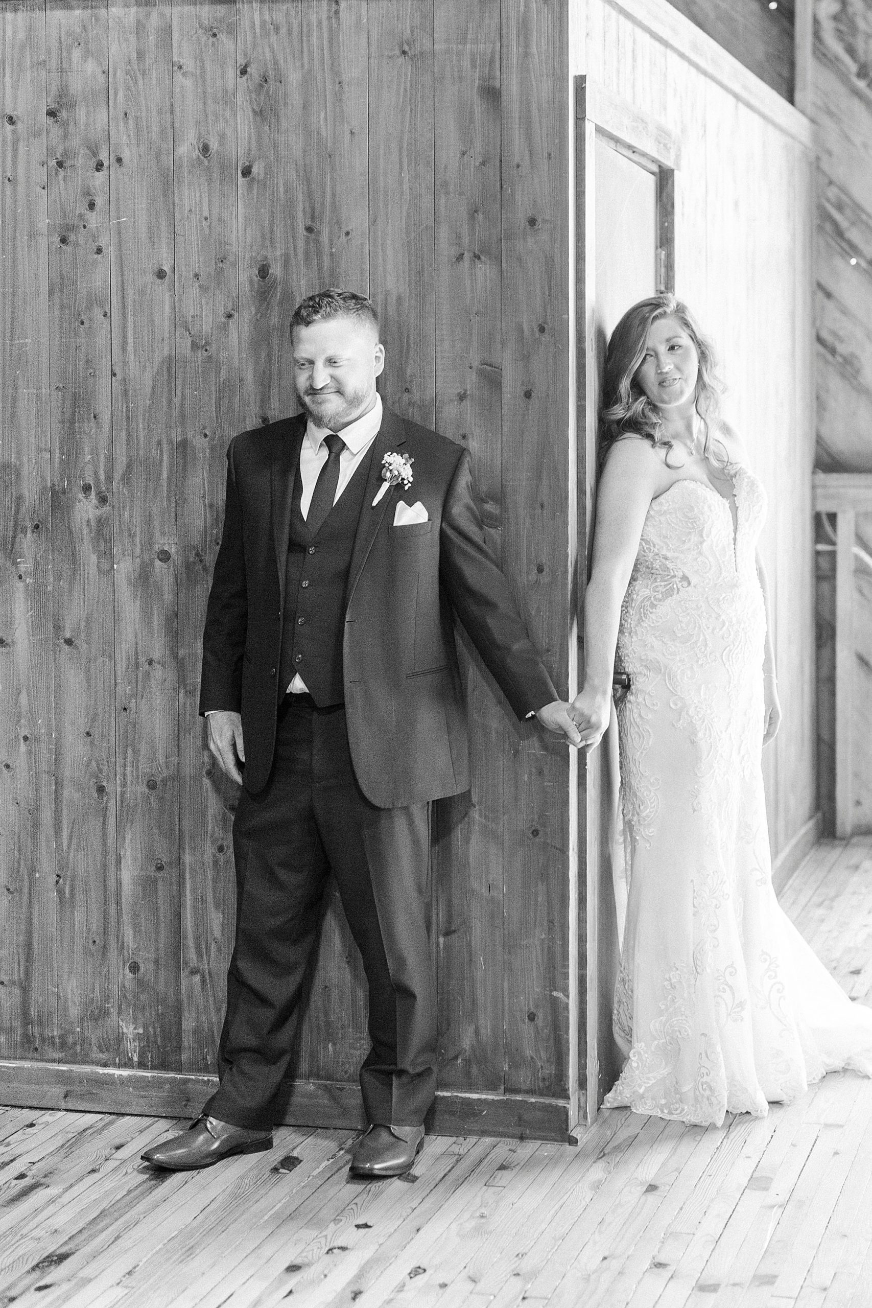 bride and groom have first touch around corner at The Dairy Barn