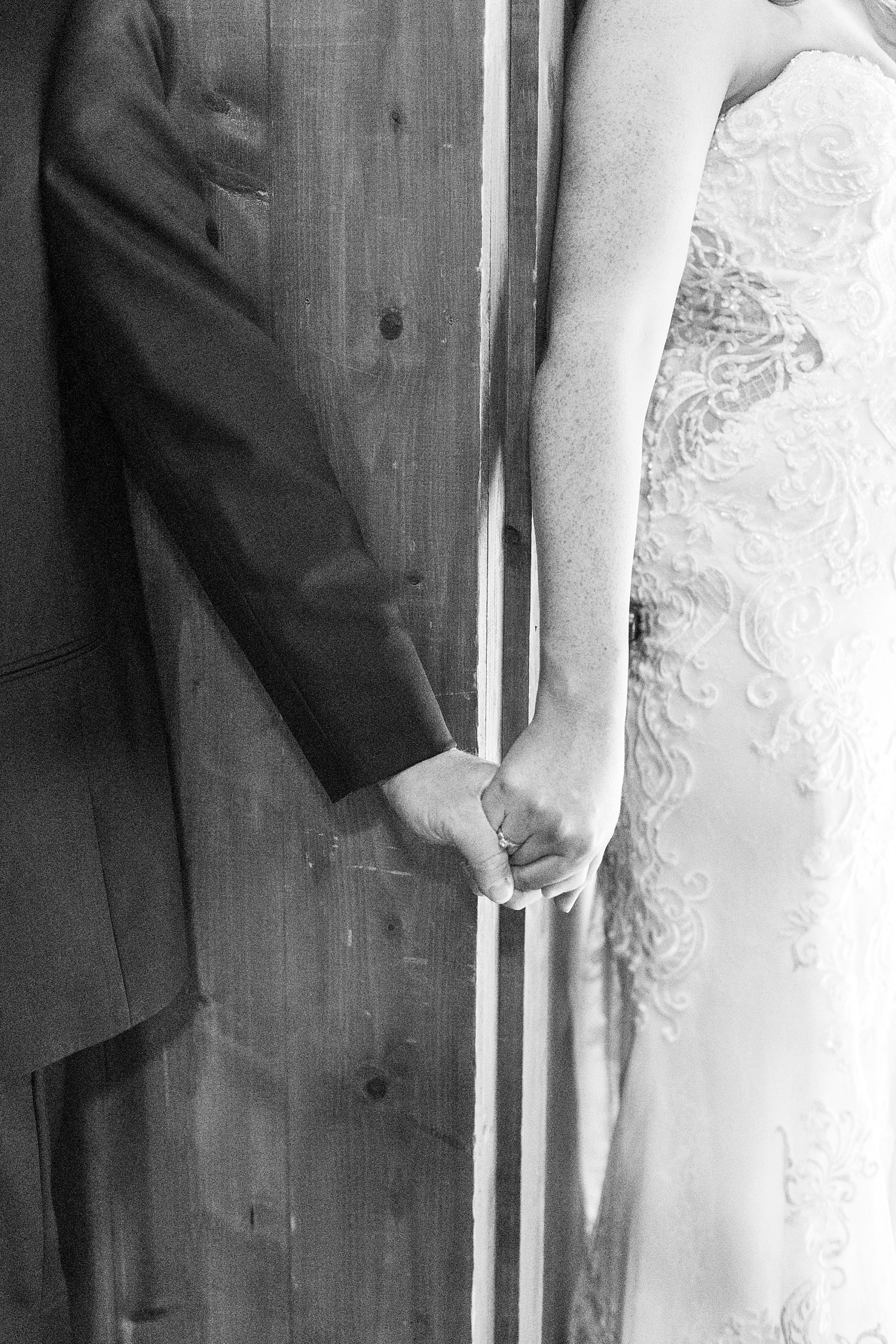 bride and groom hold hands around wall during first touch