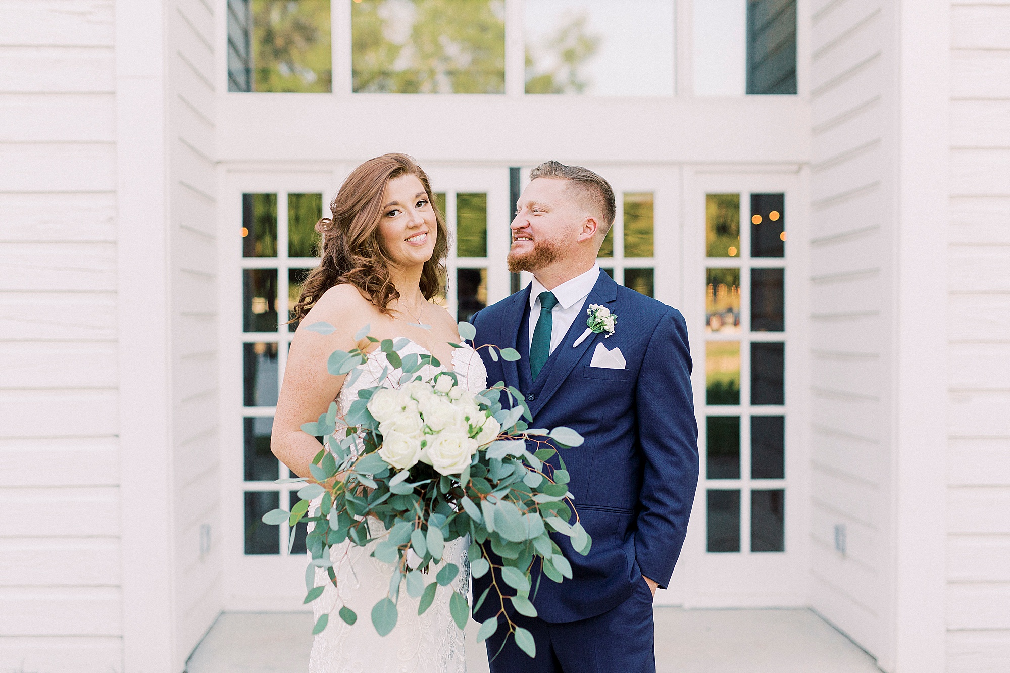 groom looks at bride during portraits outside The Dairy Barn