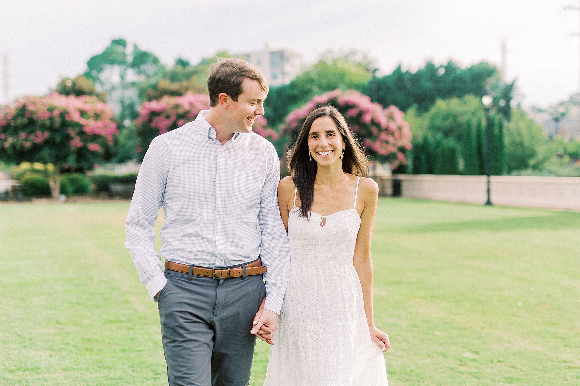 couple holds hands walking through Midtown Park